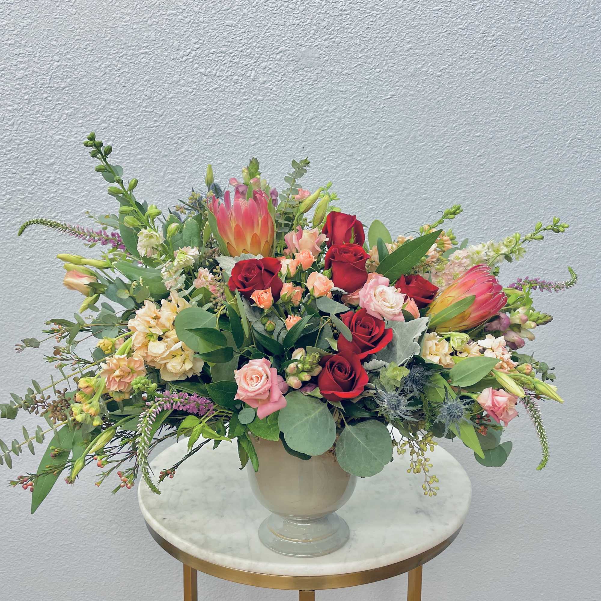 Mixed bouquet of red and pink roses with tropical blooms in a vase