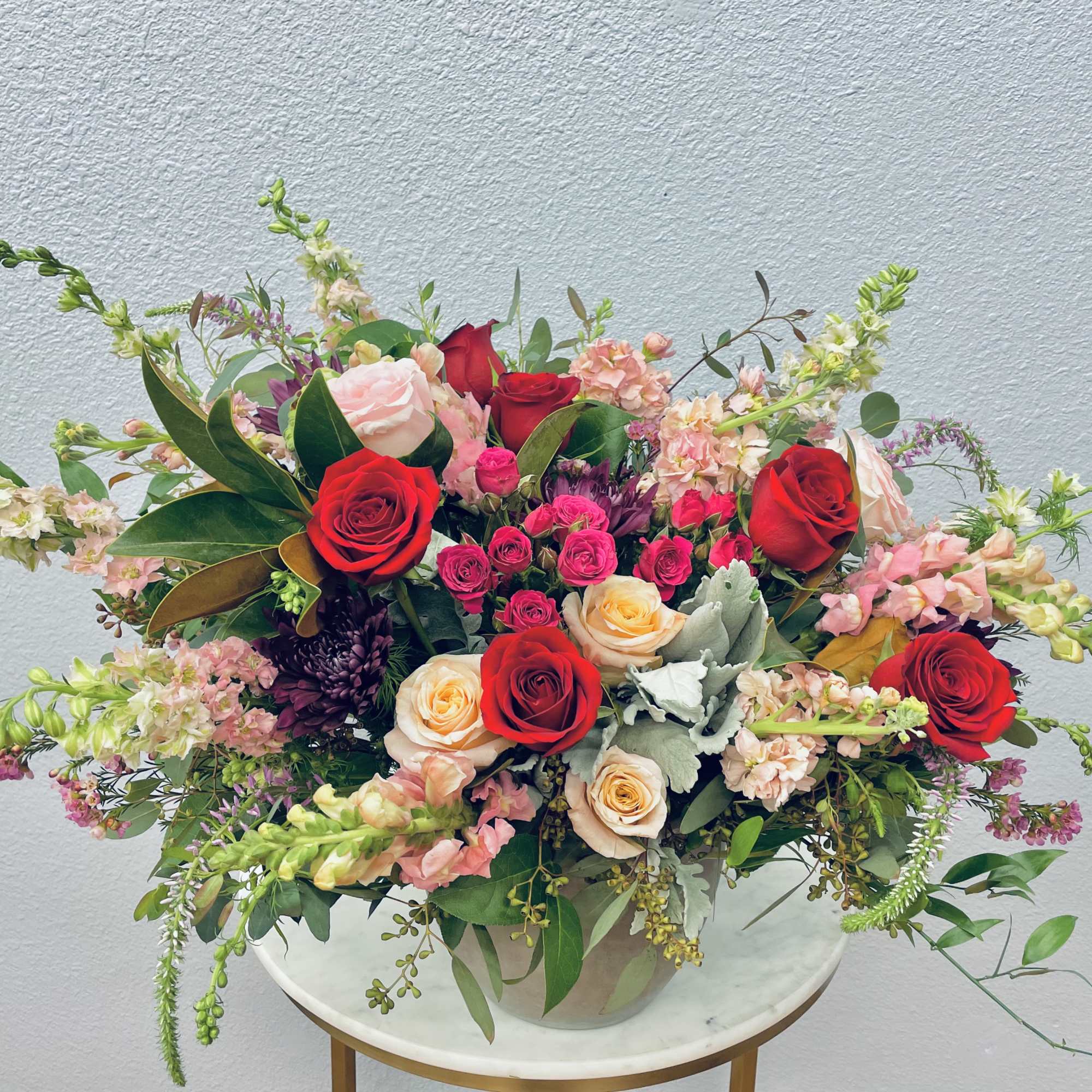 Large mixed bouquet of red, pink, and peach roses in a vase