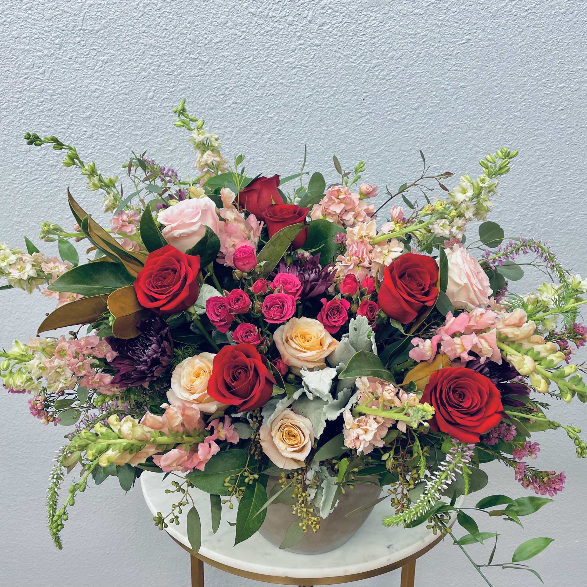 Mixed bouquet of red, pink, and cream roses in a white vase