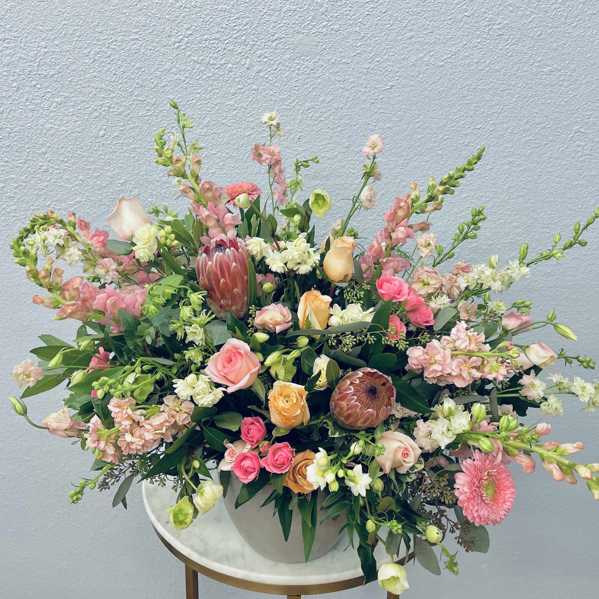Large mixed bouquet with pink, peach, and white flowers in a white vase