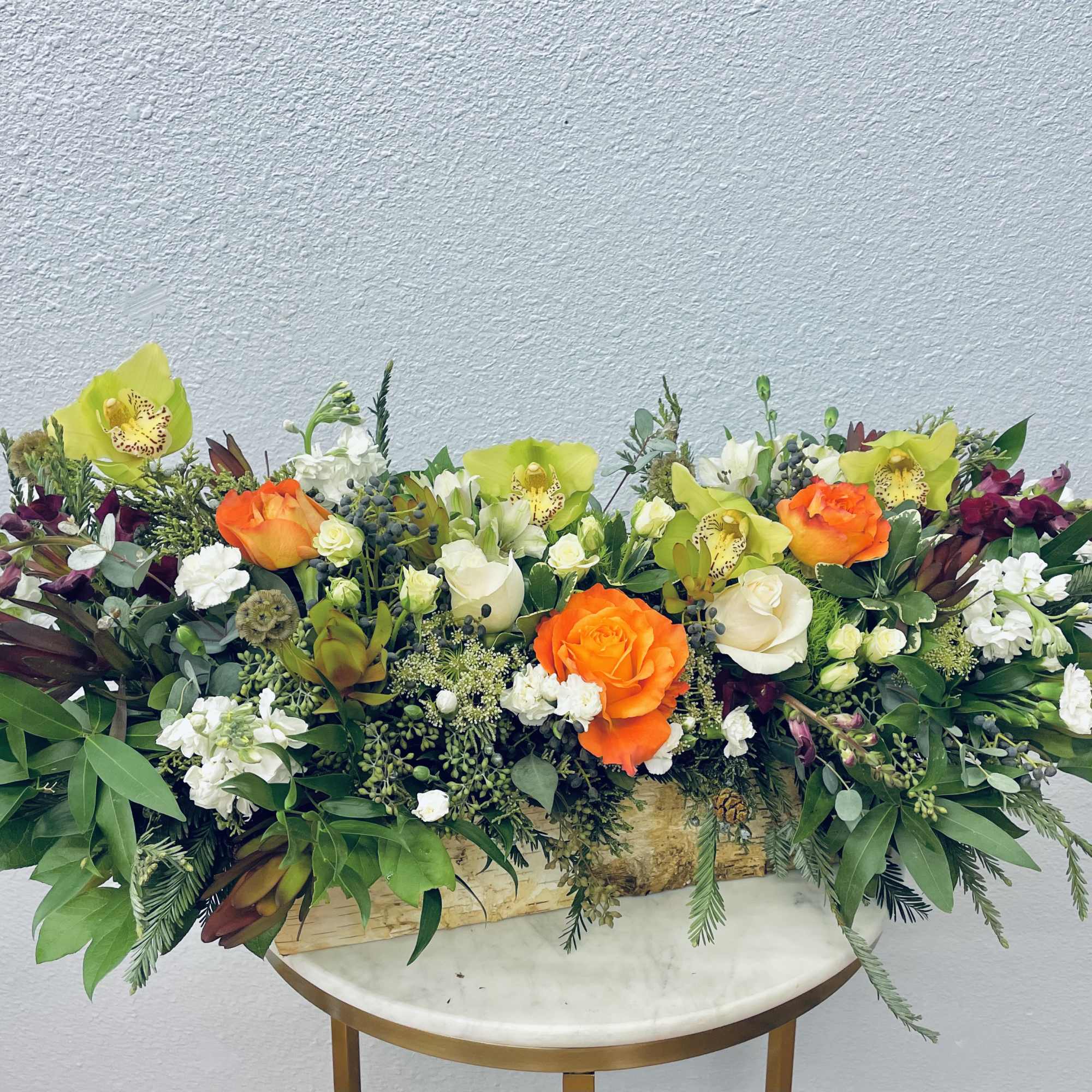 Low floral centerpiece with orange and white roses and green orchids