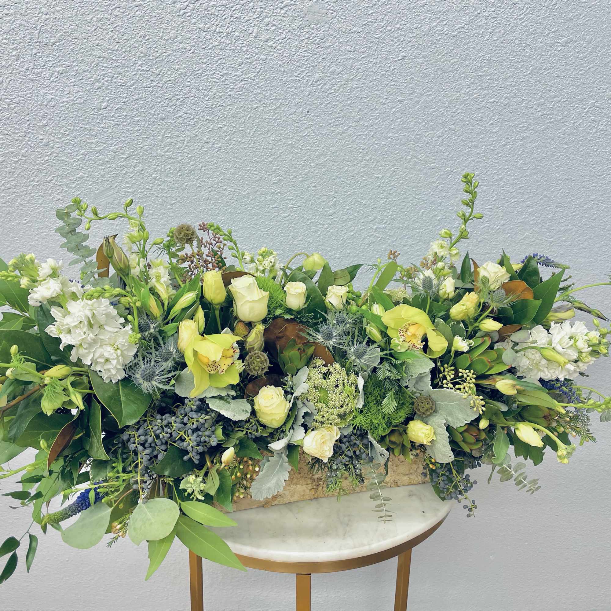 Large floral centerpiece with pale yellow and white blooms in a low container
