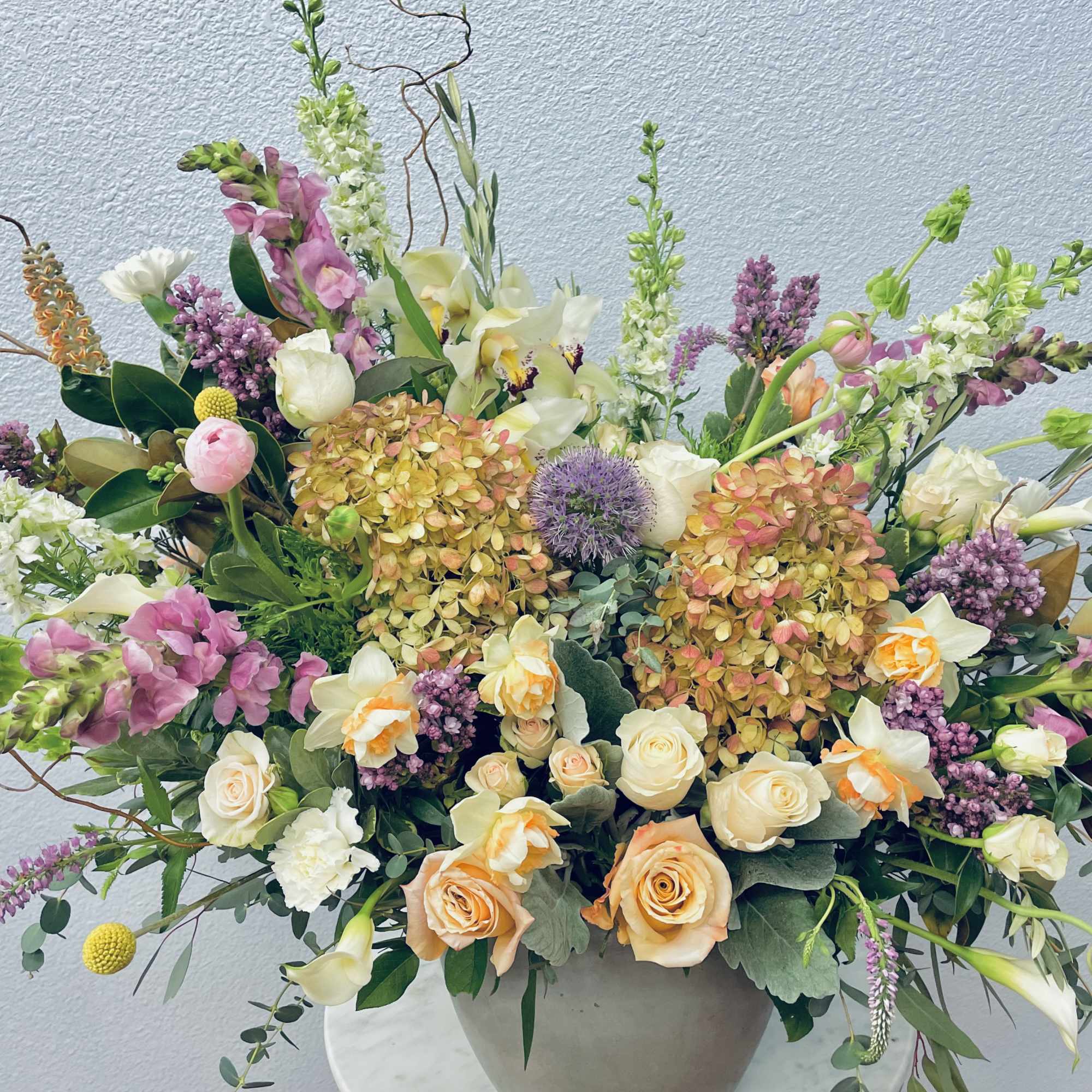 Large mixed floral arrangement in a round vase with pink, white, and peach blooms