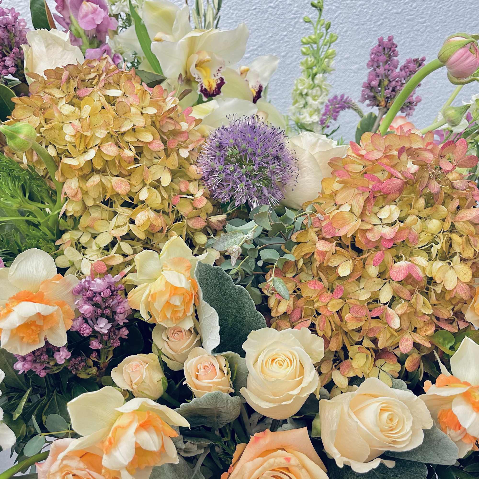 Mixed bouquet with cream roses, daffodils, hydrangeas, and purple blooms