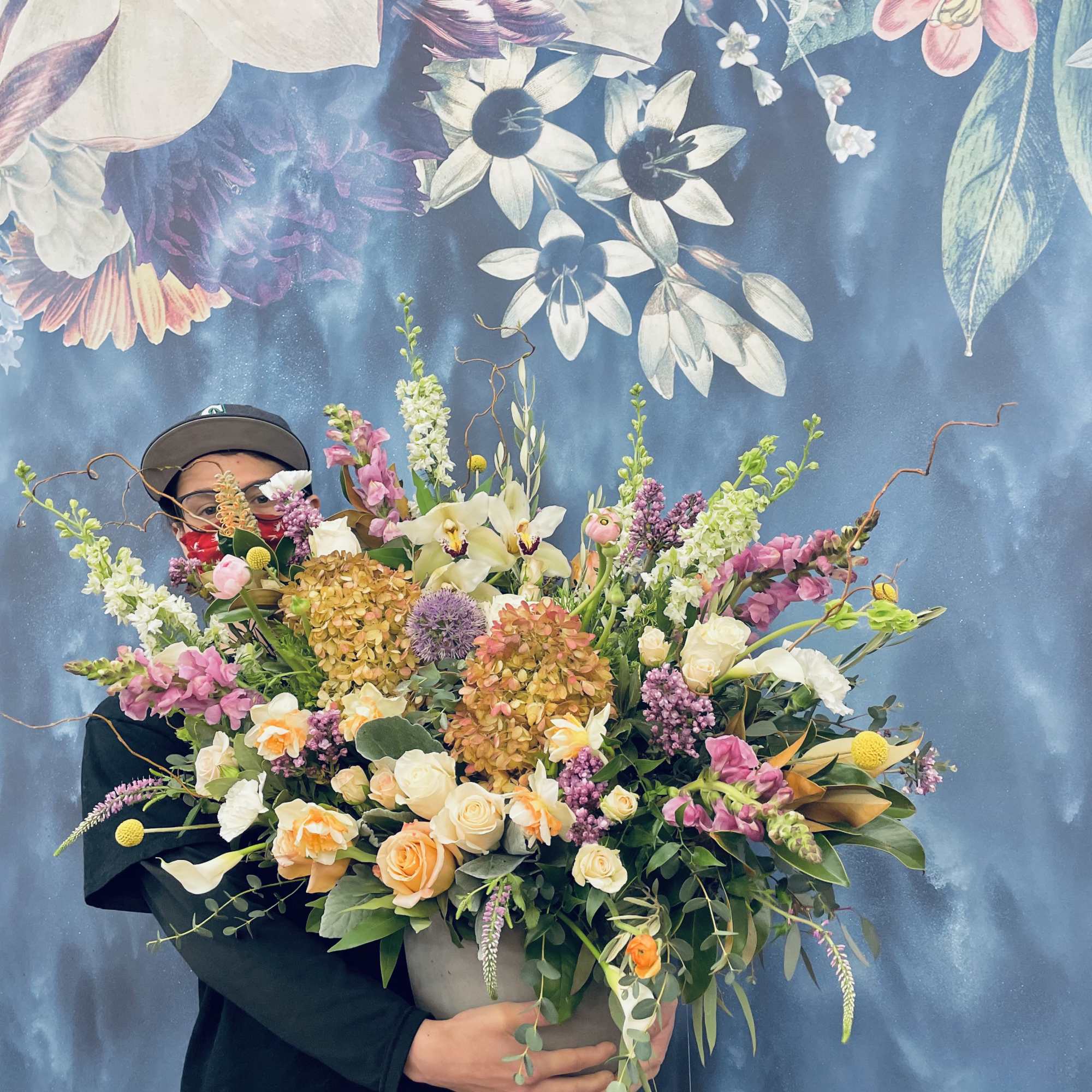 Person holding a large mixed bouquet with roses and lilies