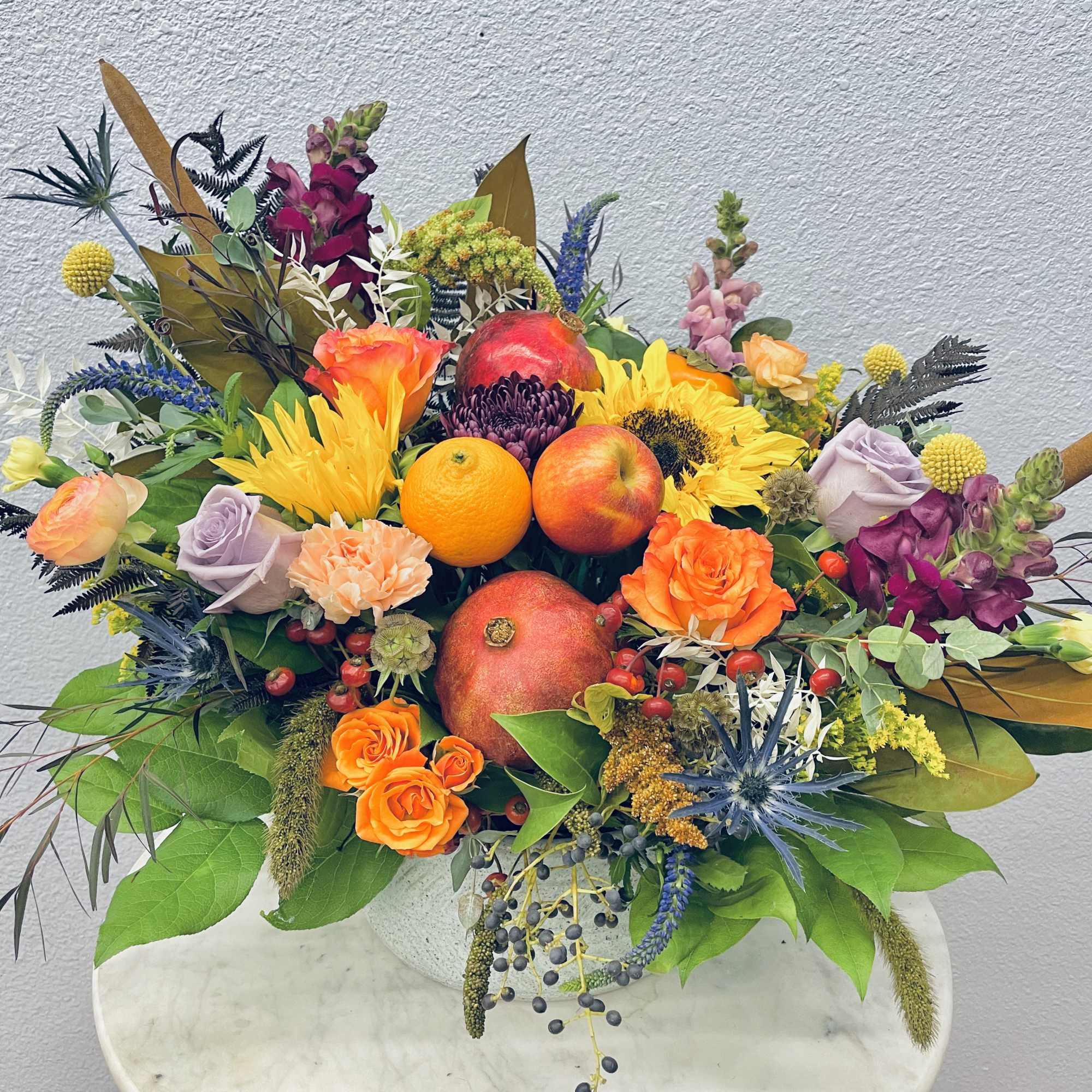 Colorful fruit and flower arrangement in a white container