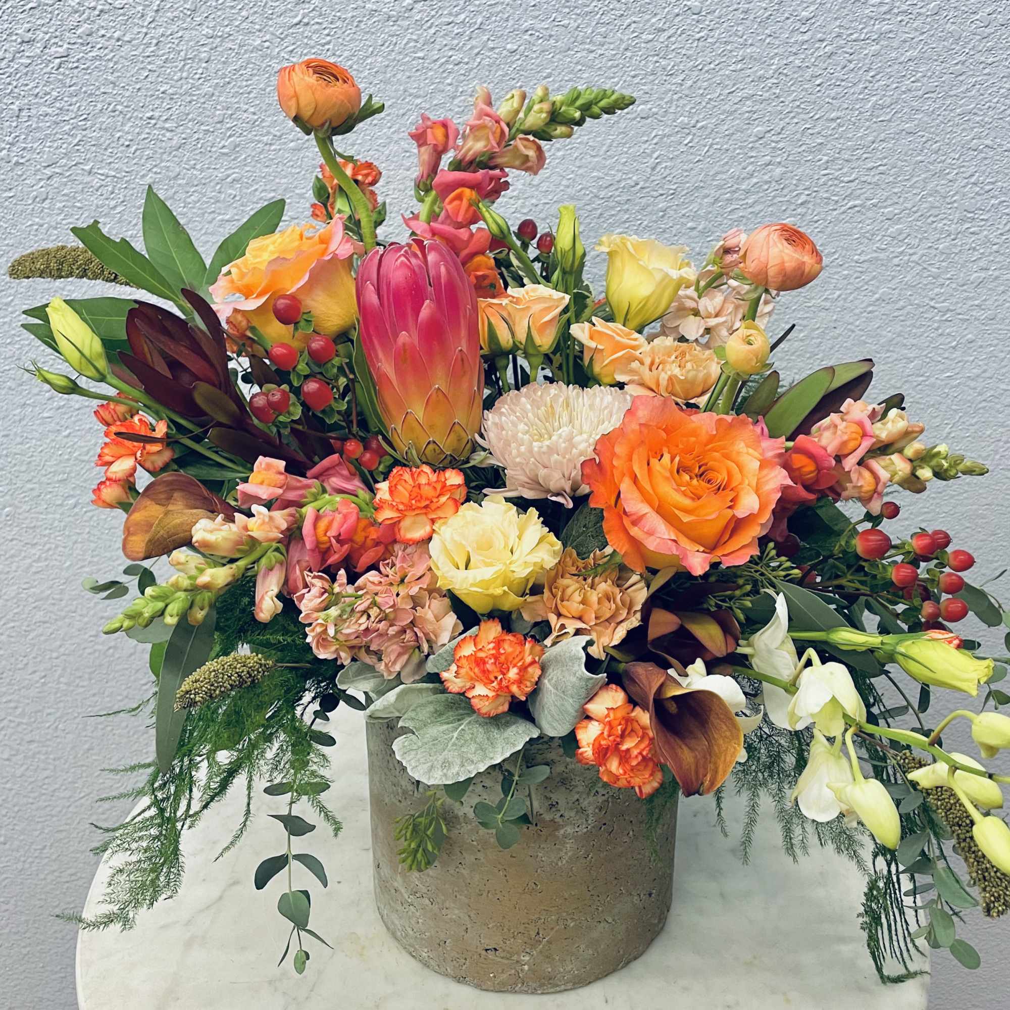 Colorful mixed floral arrangement in a concrete vase