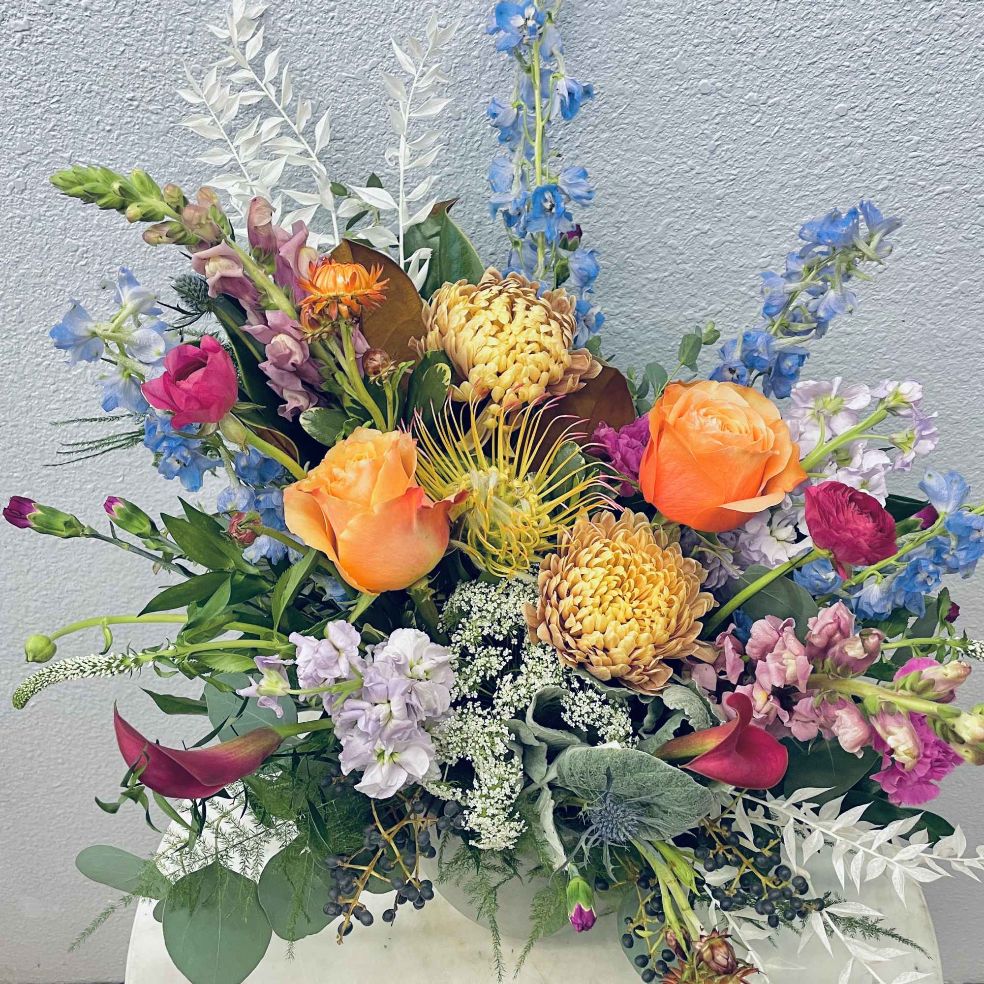 Colorful mixed flower arrangement with orange roses and blue blooms