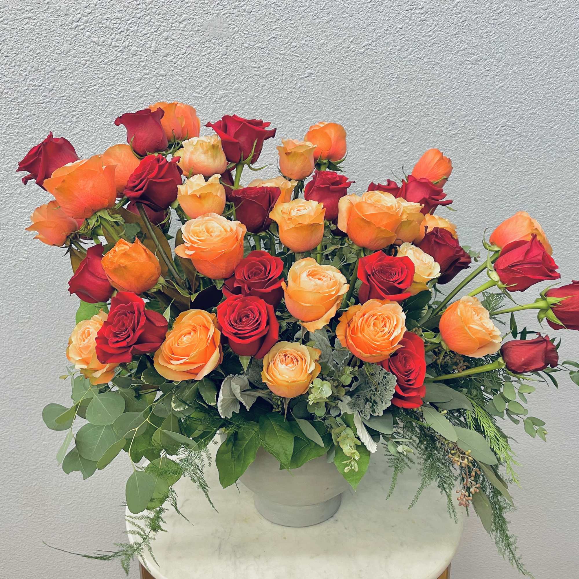 Bouquet of red and orange roses in a white vase
