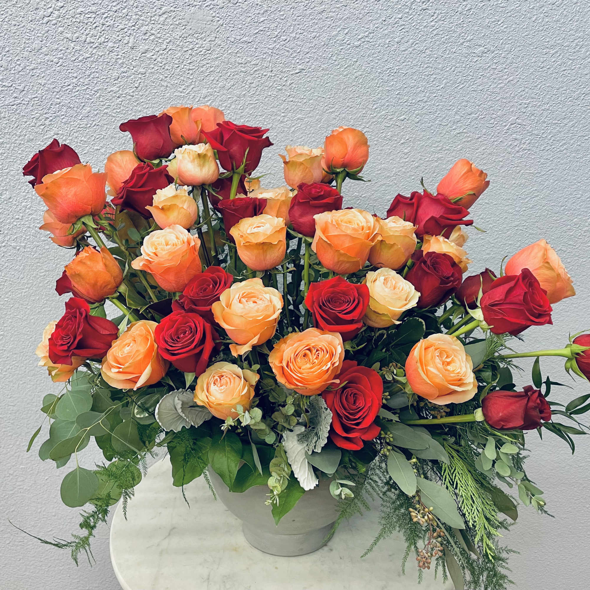 Bouquet of red and orange roses in a white vase, photo 2 of 4