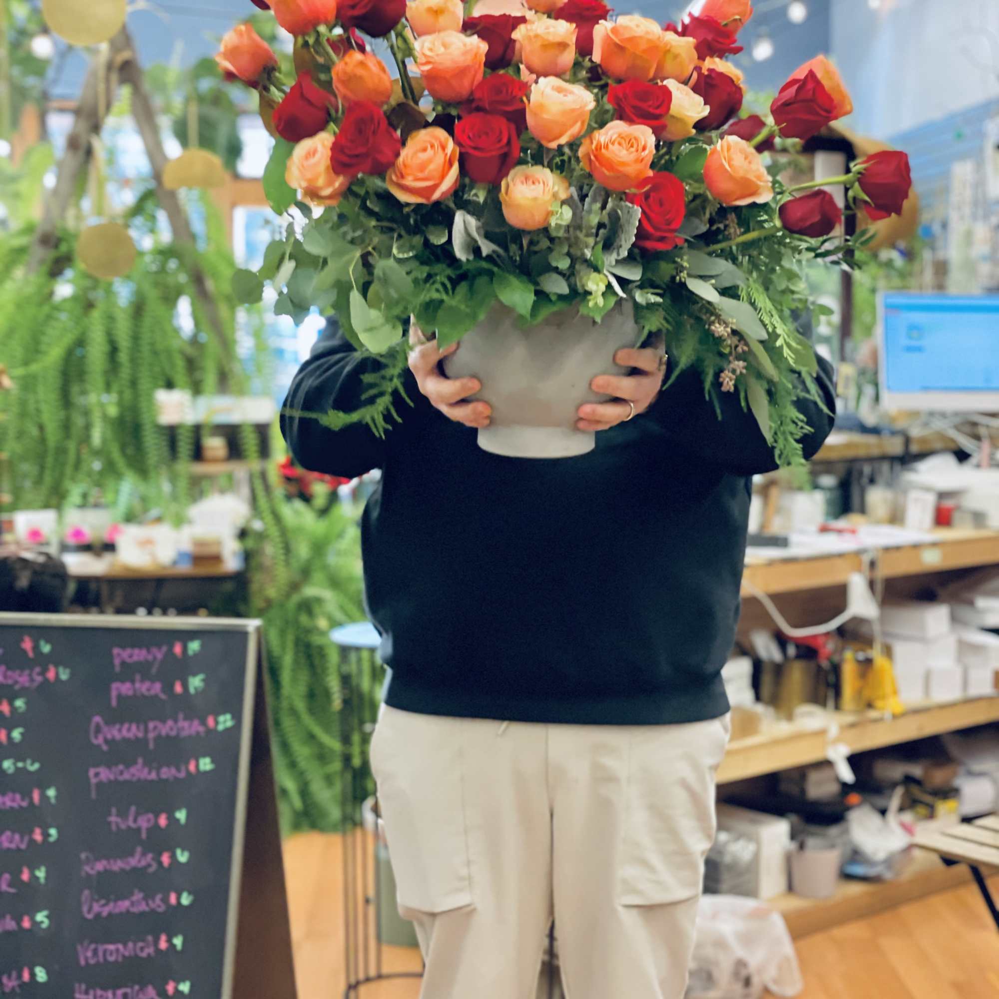 Large bouquet of red and peach roses in a white vase