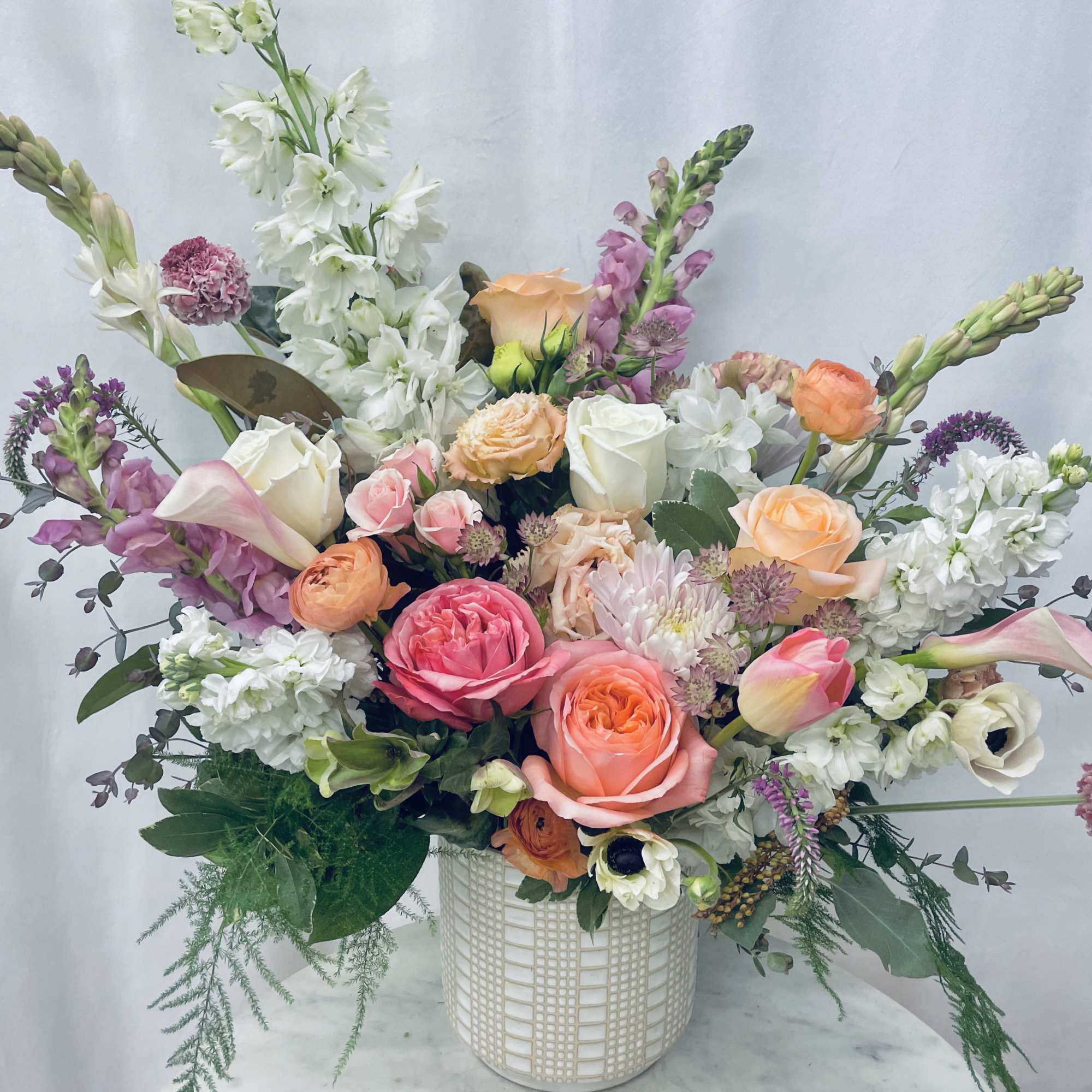 Mixed pastel flower arrangement in a white textured vase