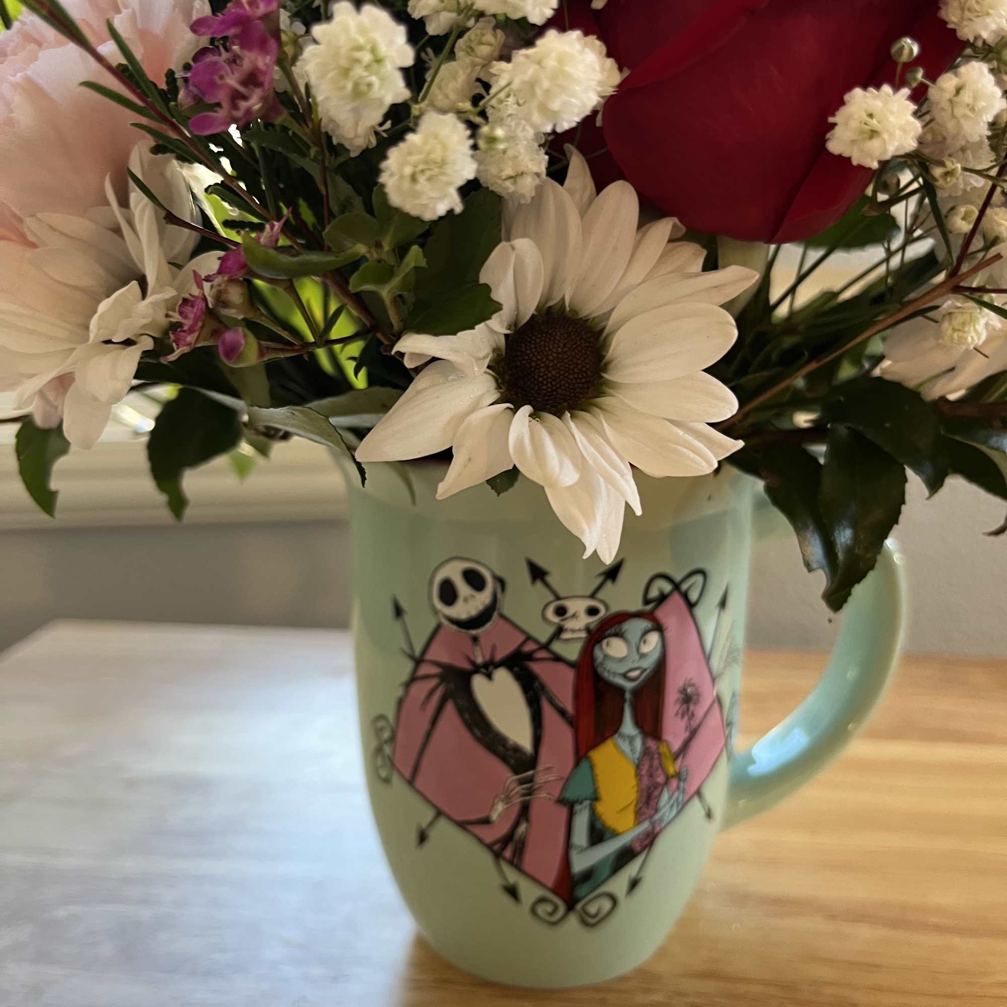 Bouquet of red roses and white daisies in a mint mug