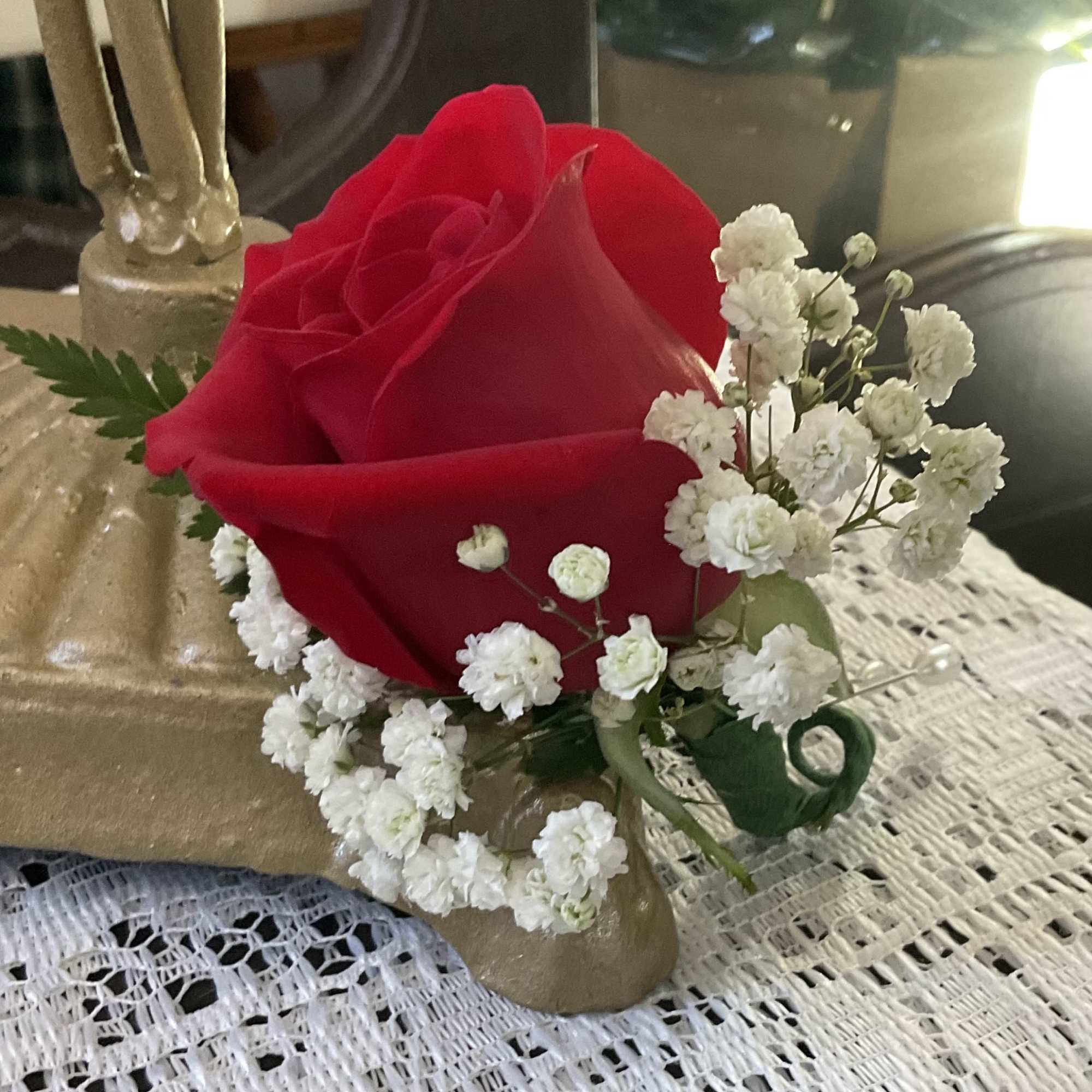 Single red rose with white baby's breath in a gold holder
