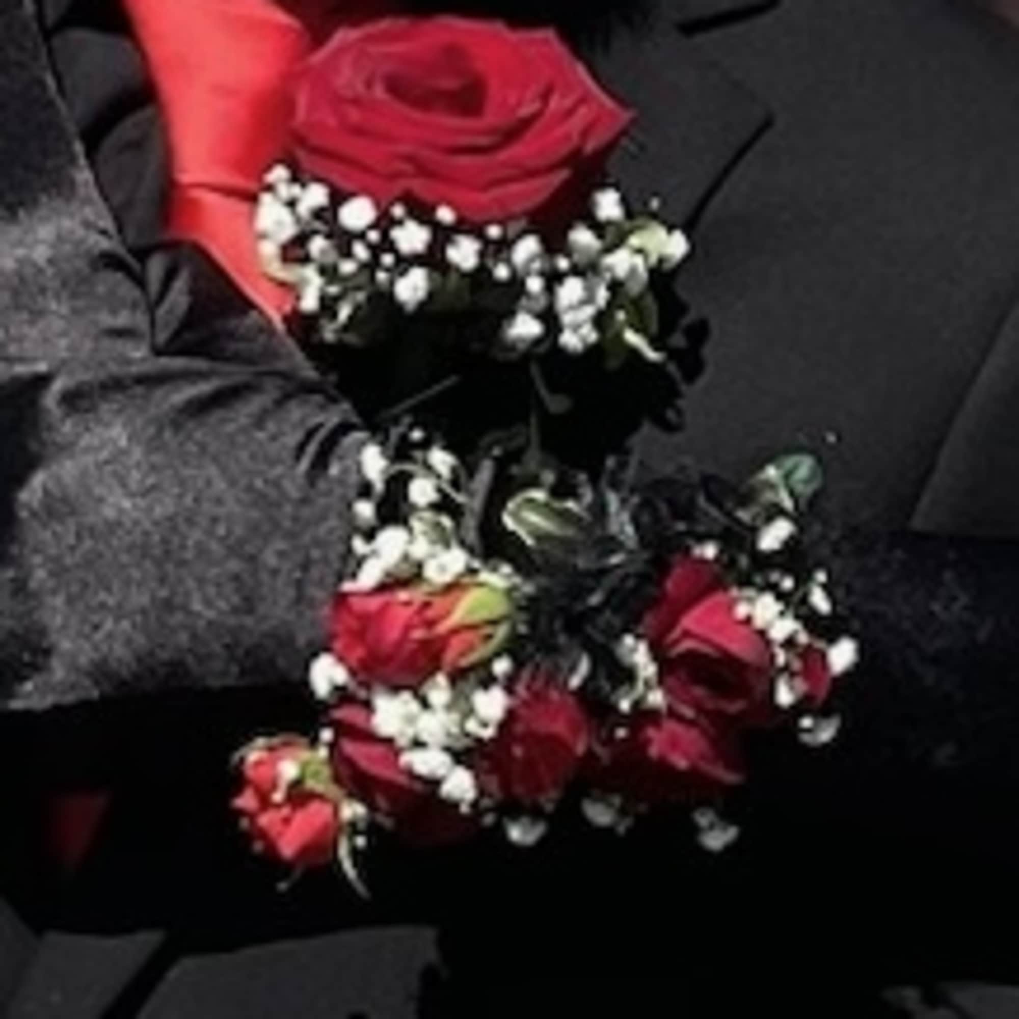 Red rose boutonniere with baby's breath on a dark suit