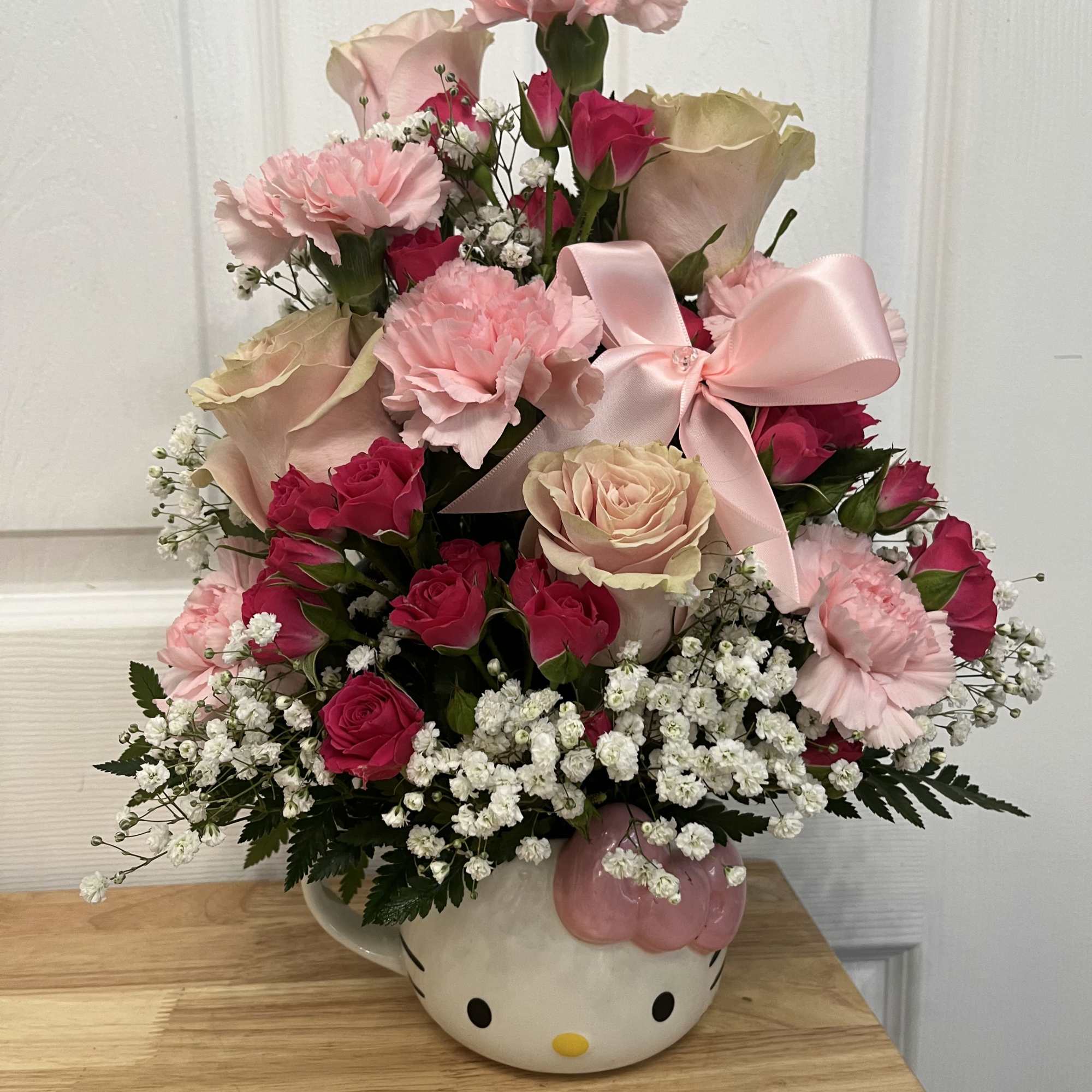 Pink and cream rose bouquet in a Hello Kitty vase with a pink bow