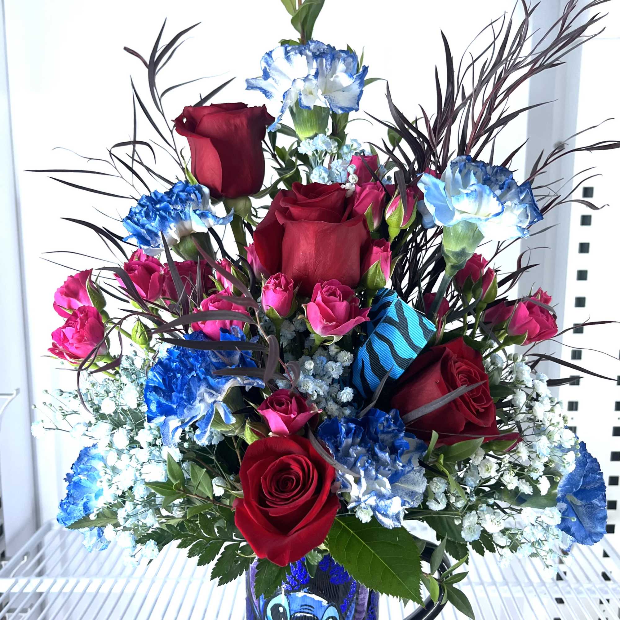Red roses and blue carnations in a Stitch mug