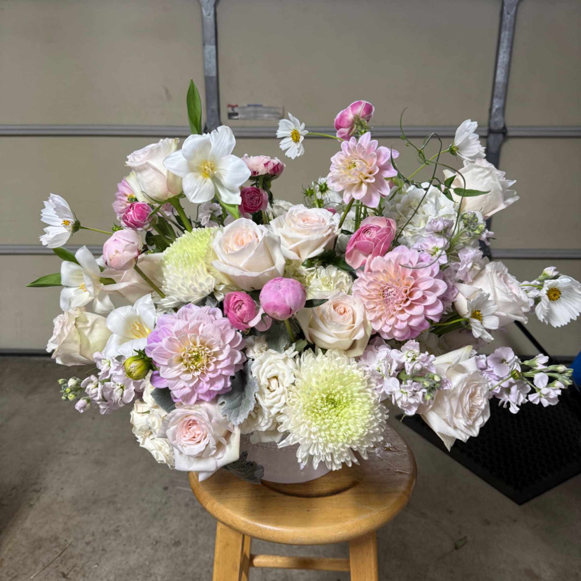 Large pastel bouquet of roses, dahlias, and white daisies in a vase
