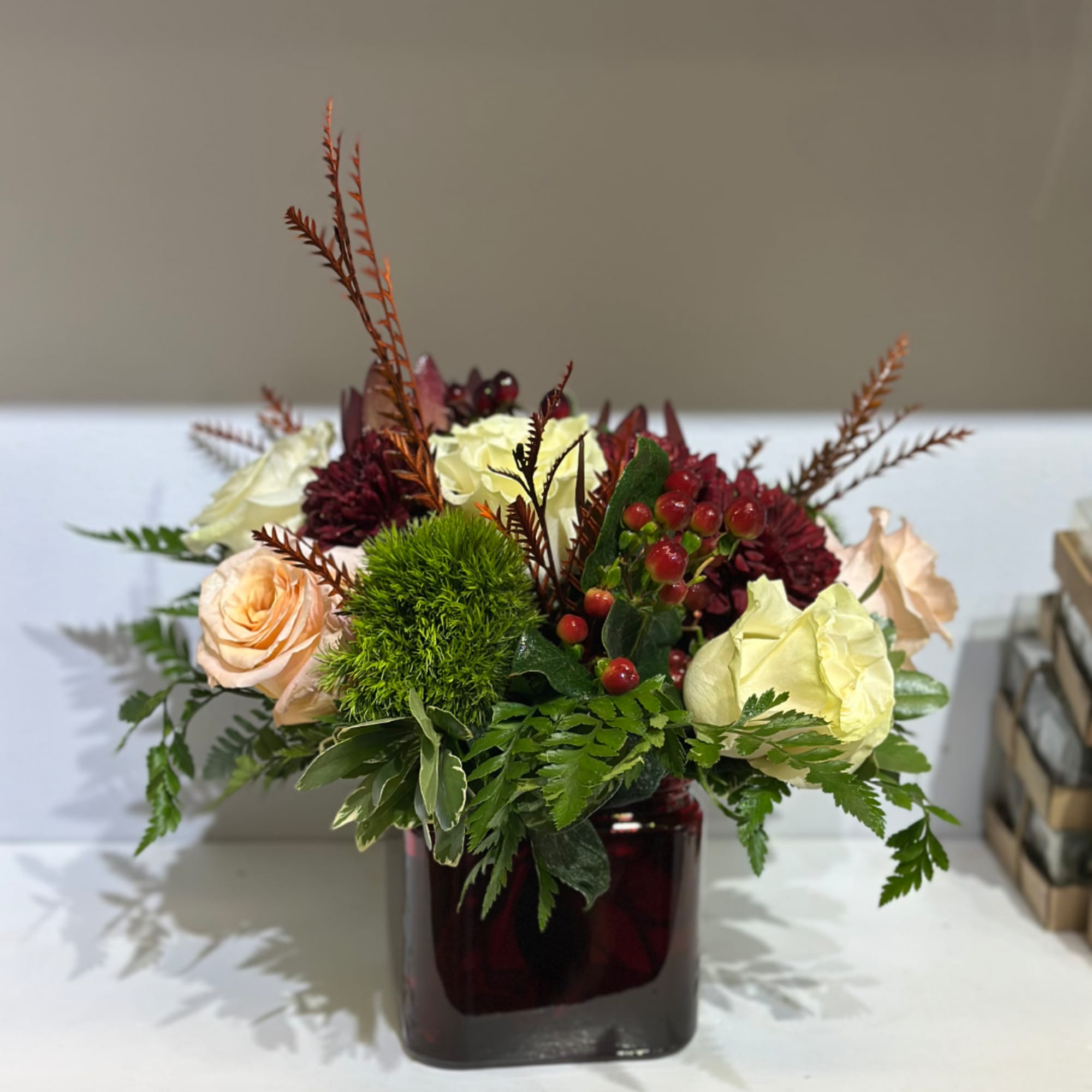 Mixed bouquet in a dark glass vase with cream and peach roses
