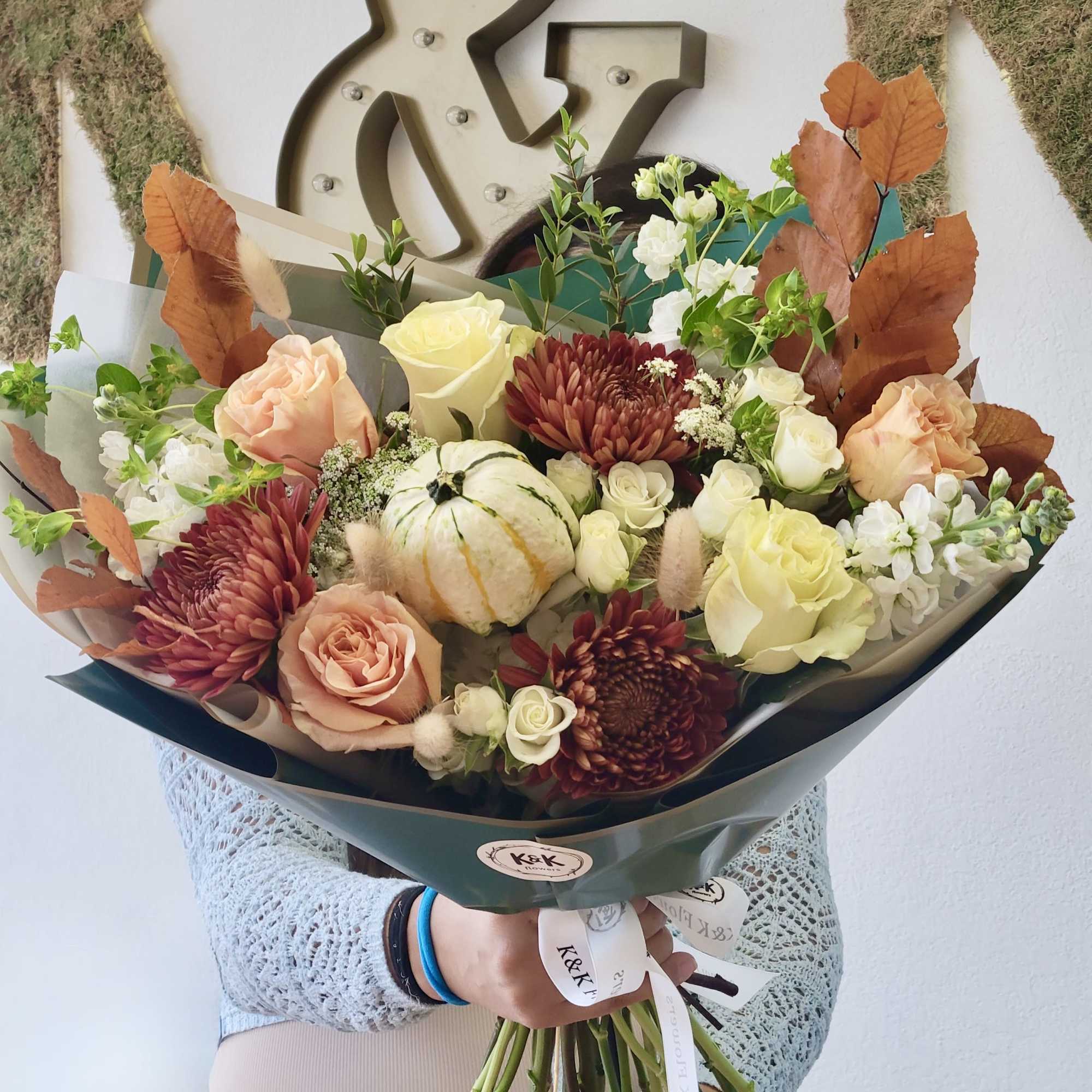 Handheld bouquet with roses, chrysanthemums, and a small pumpkin centerpiece