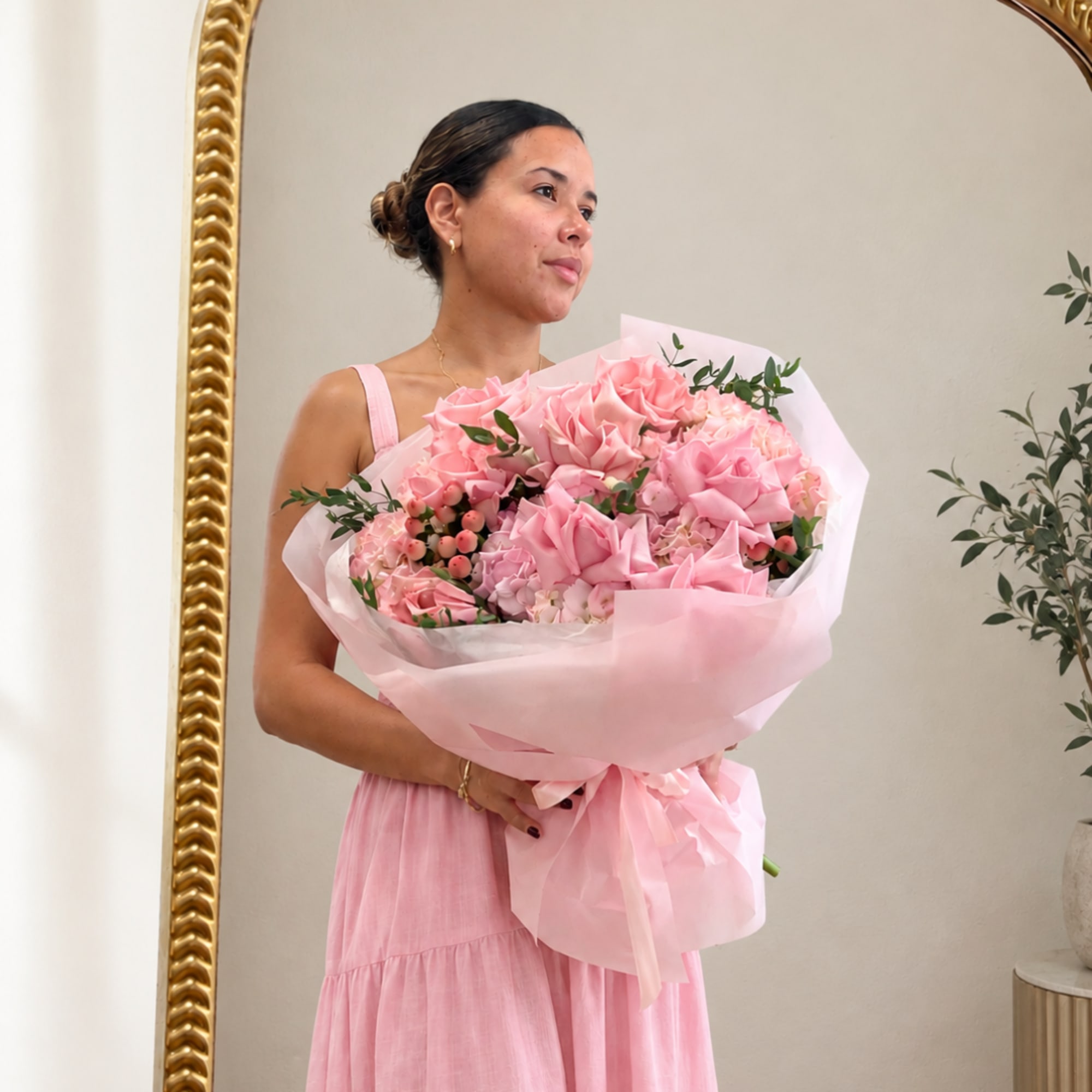 Woman holding a large pink bouquet wrapped in pale pink paper