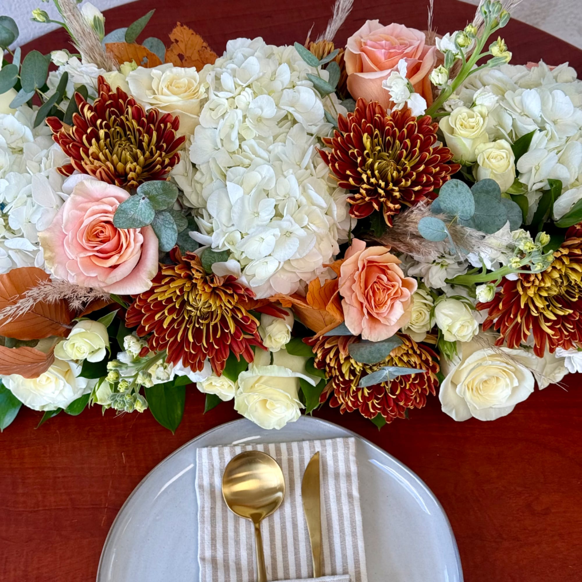 Floral centerpiece with white hydrangeas, roses, and peach blooms on a table