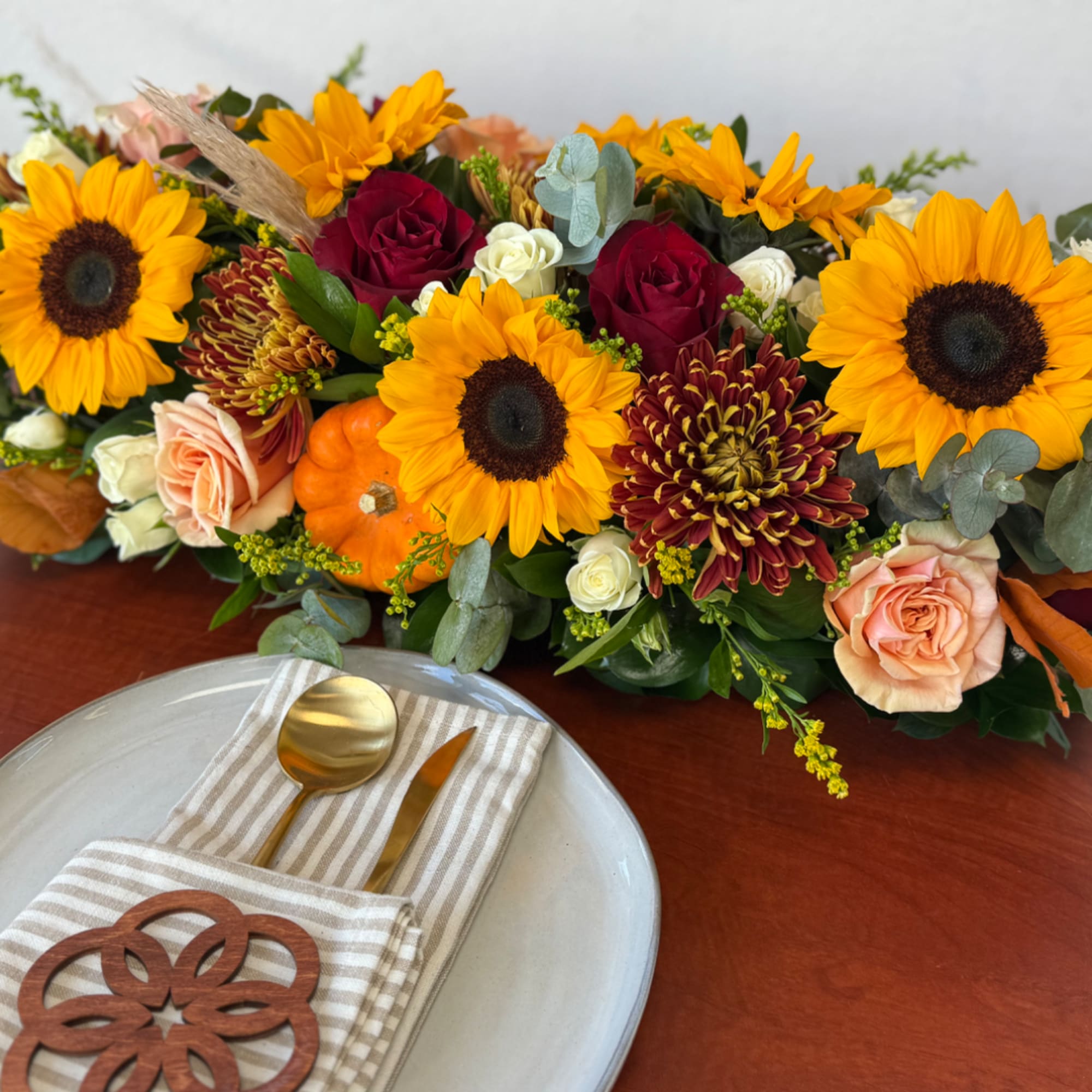 Sunflower and rose centerpiece with pumpkins on a table