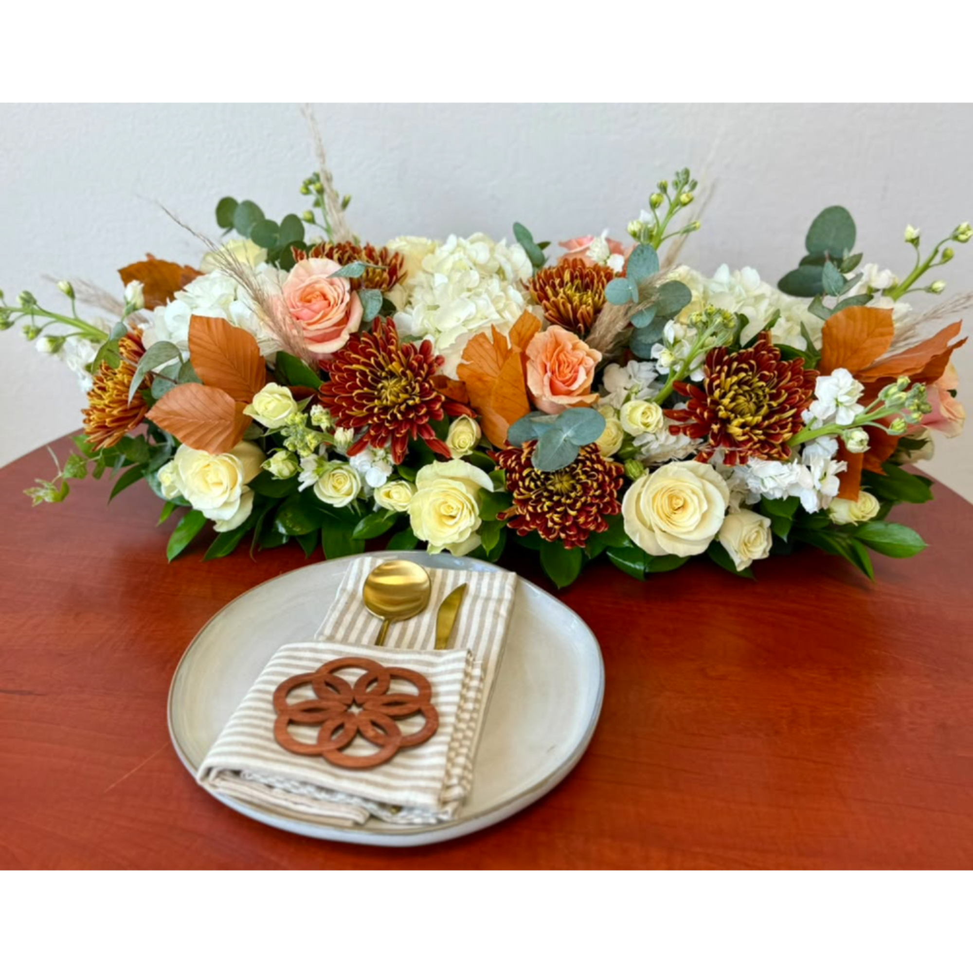Low floral centerpiece with cream roses, mums, and peach blooms