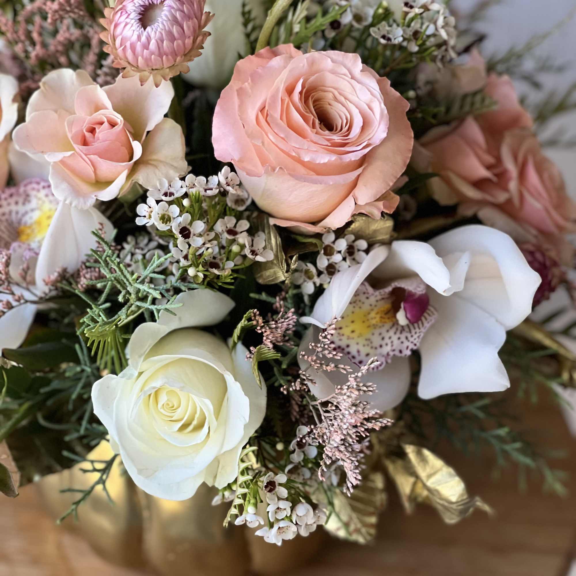 Pink and white floral bouquet with roses and orchids in a gold vase