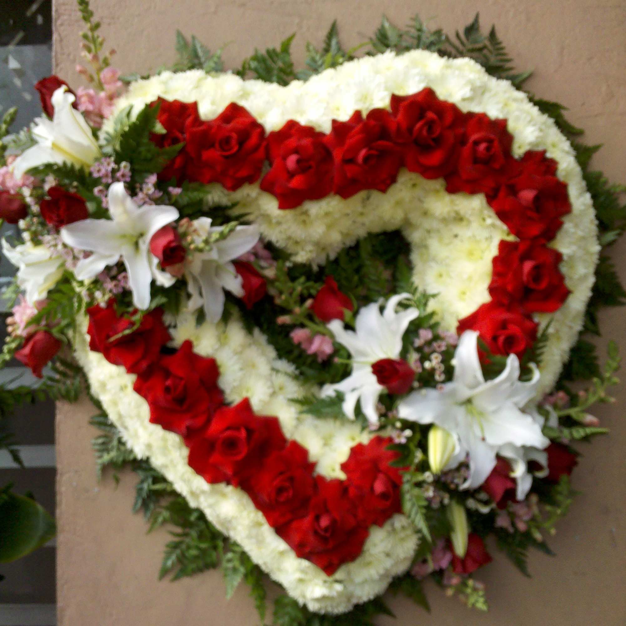 Heart-shaped floral wreath with red roses and white lilies