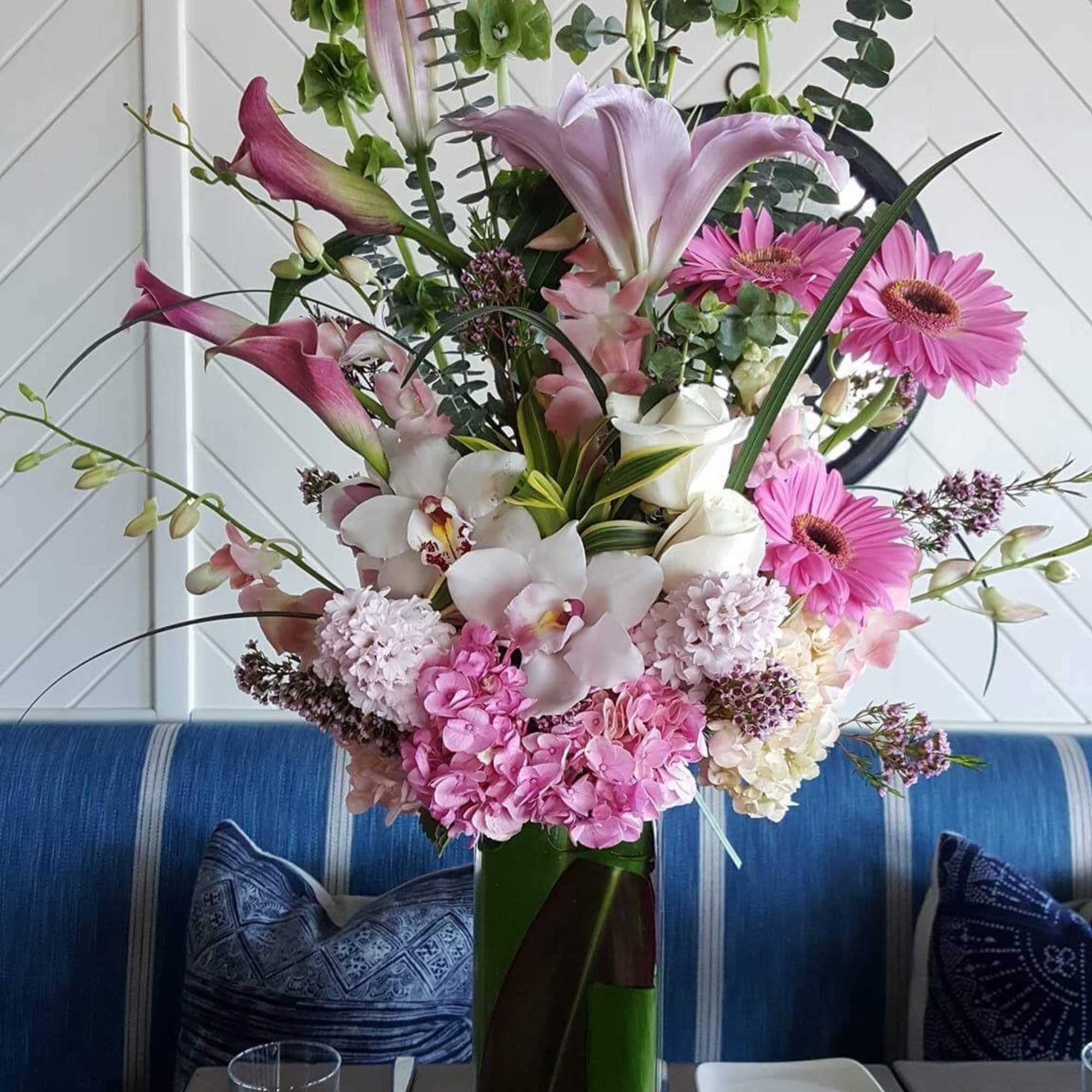 Tall pink and white floral arrangement in a green vase