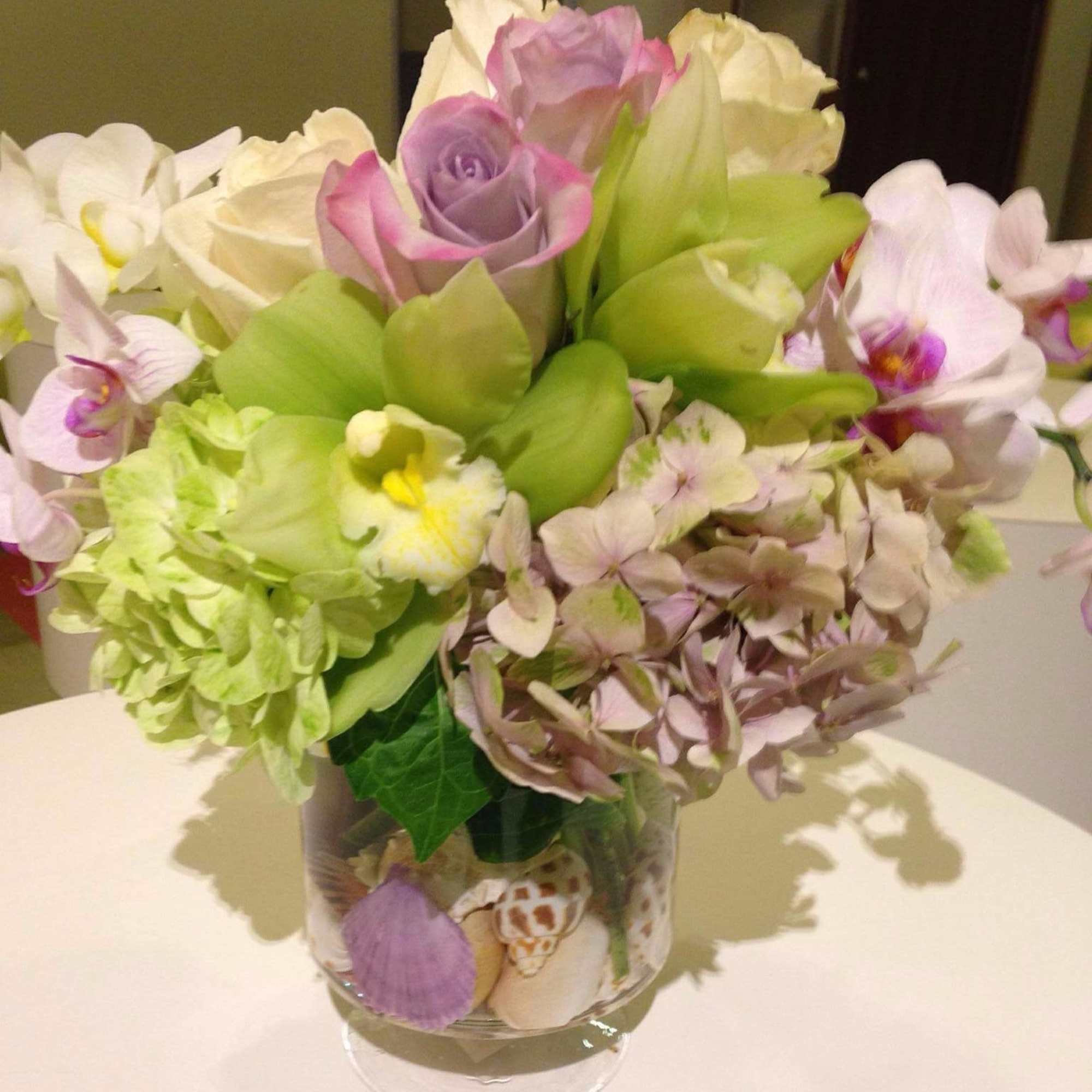 Bouquet of roses, orchids, and hydrangea in a clear glass vase