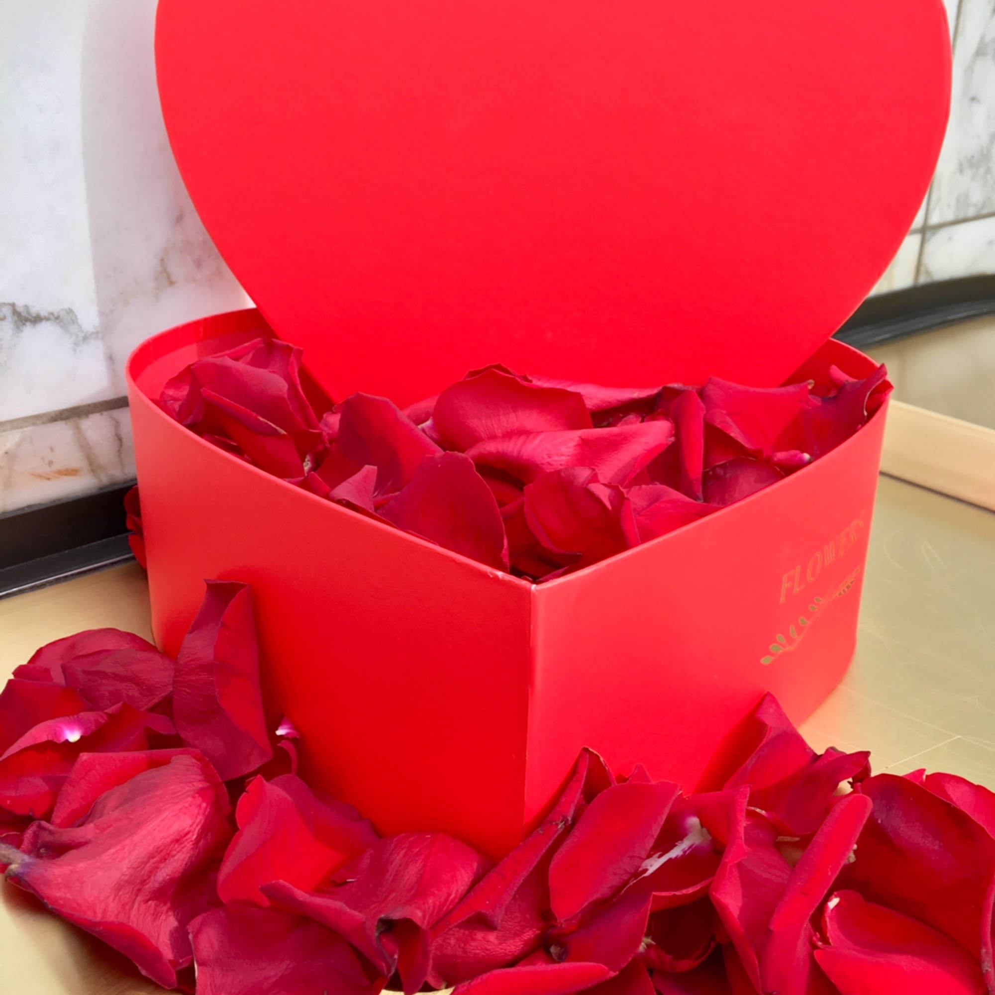 Red heart-shaped gift box filled with rose petals, photo 2 of 4