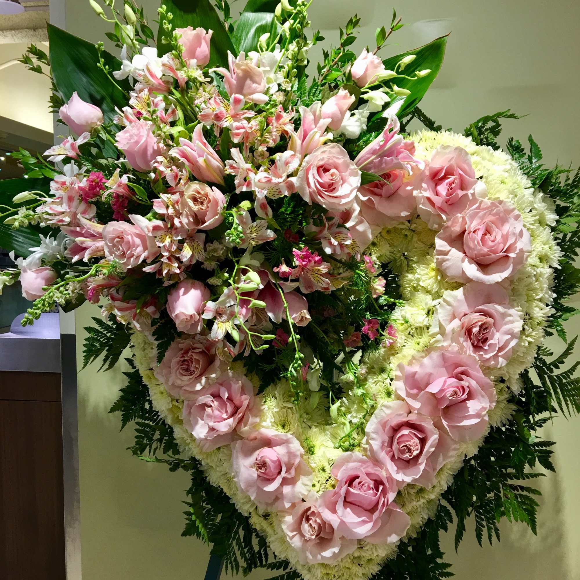 Large pink rose and lily funeral spray on an easel