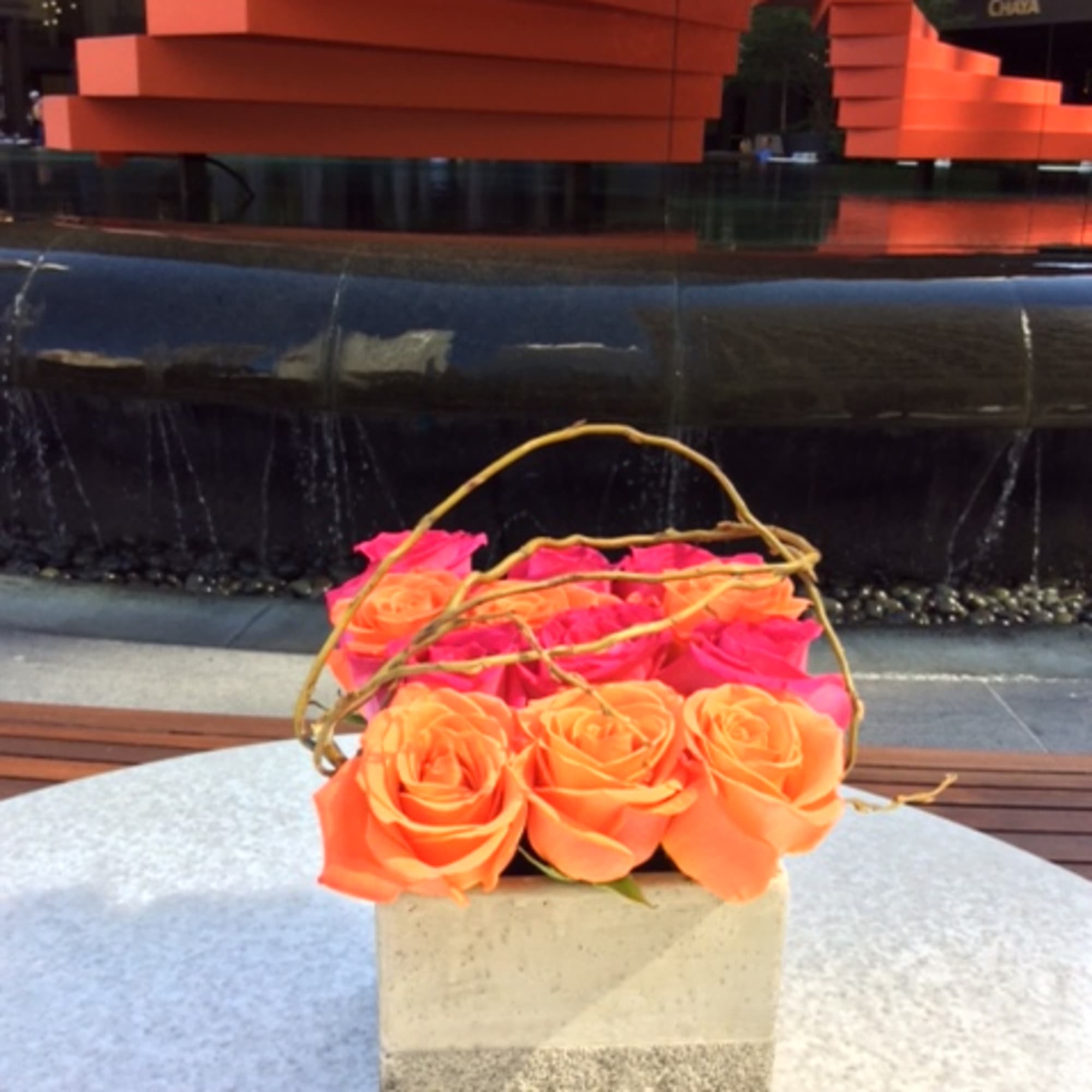 Basket of orange and pink roses with a twig handle