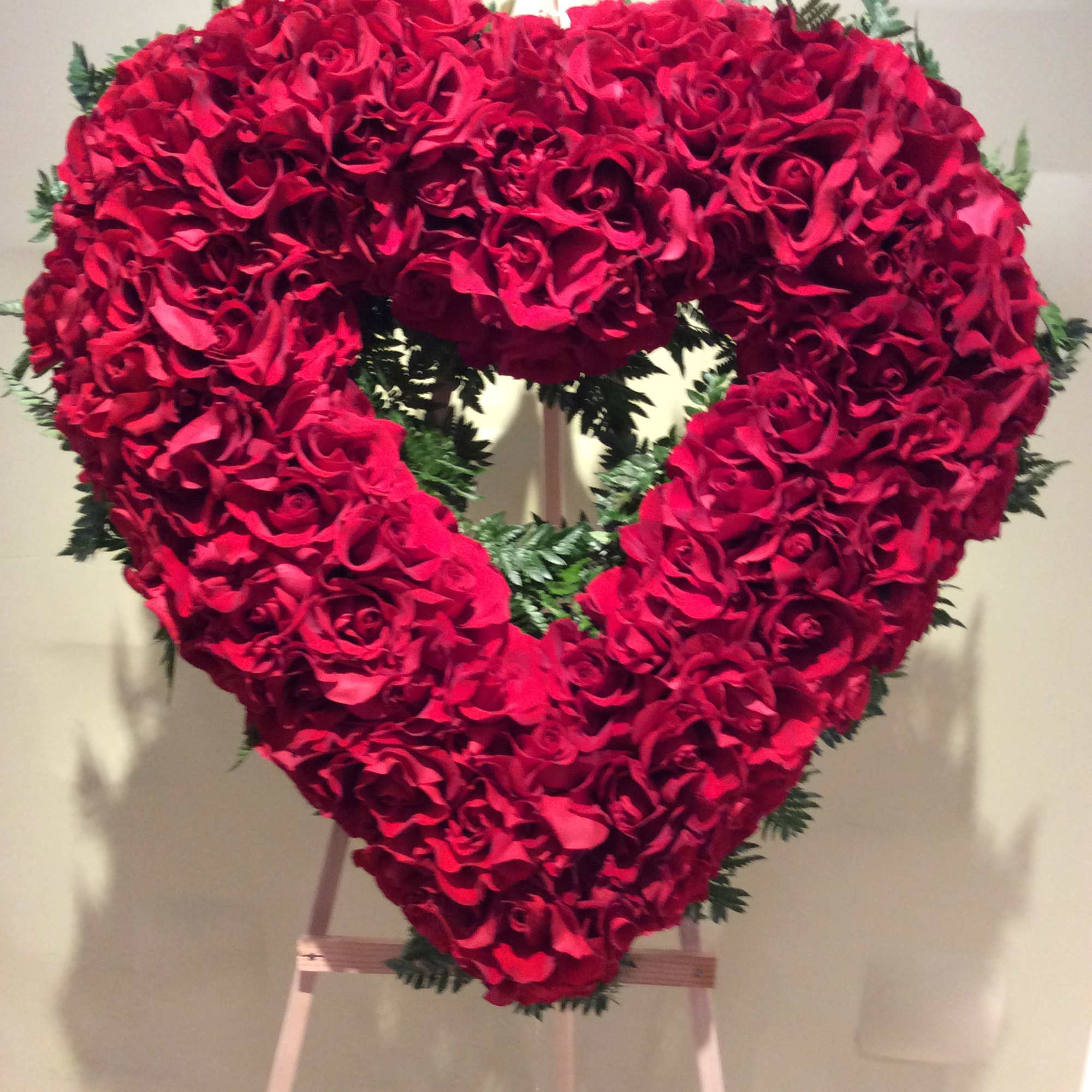 Heart-shaped red rose arrangement on an easel