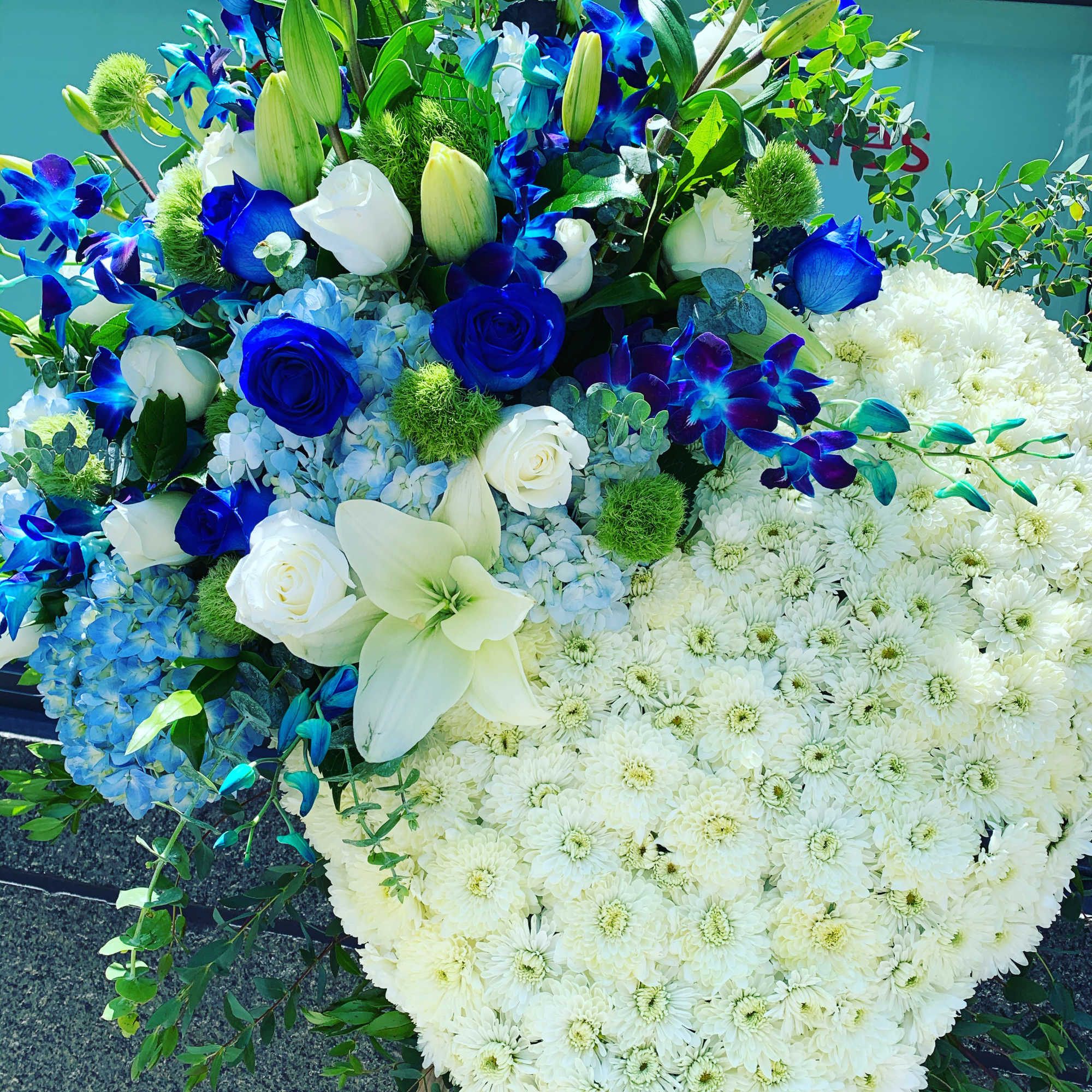 Large floral arrangement with white chrysanthemums, blue roses, and lilies