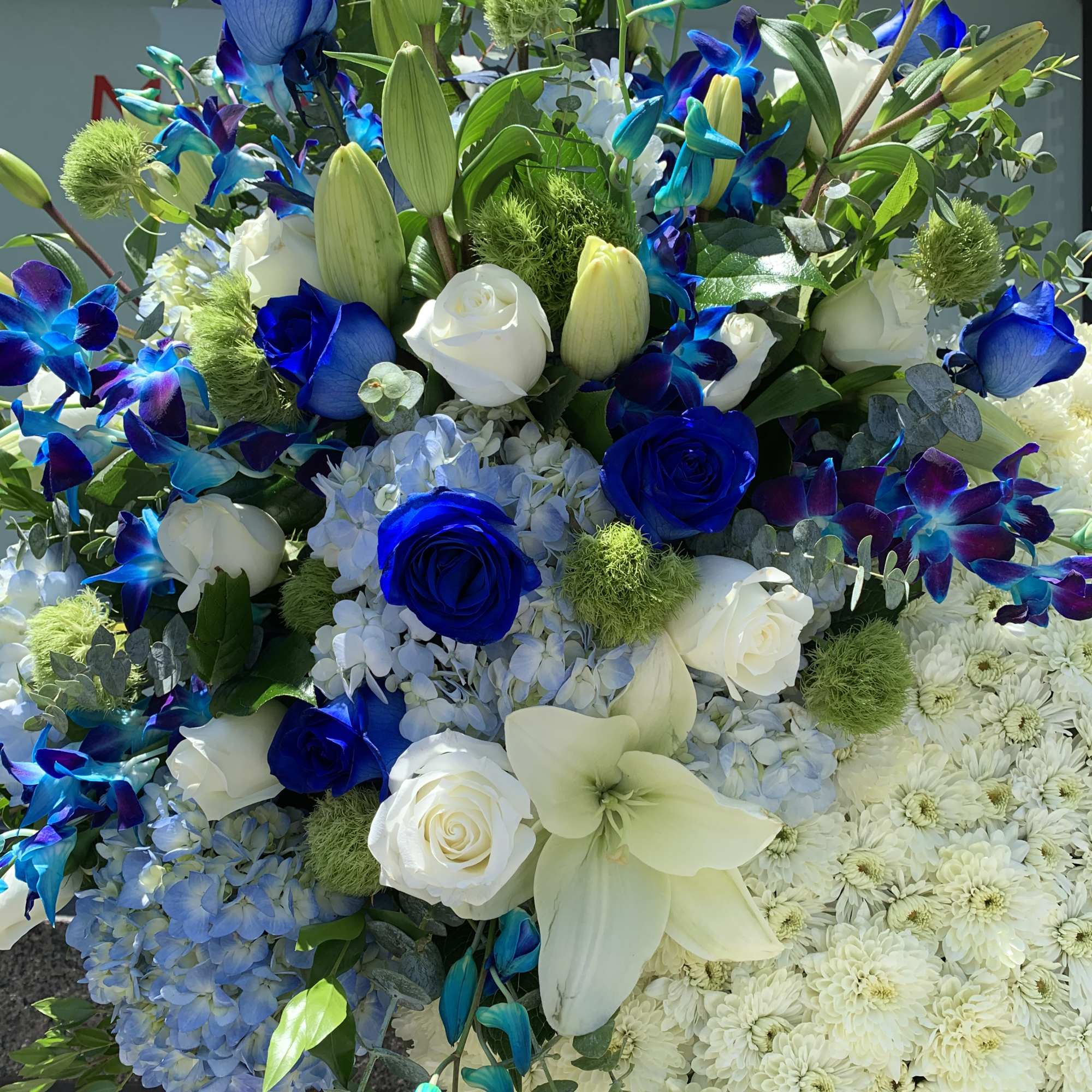 Blue and white floral arrangement with roses, lilies, and hydrangeas