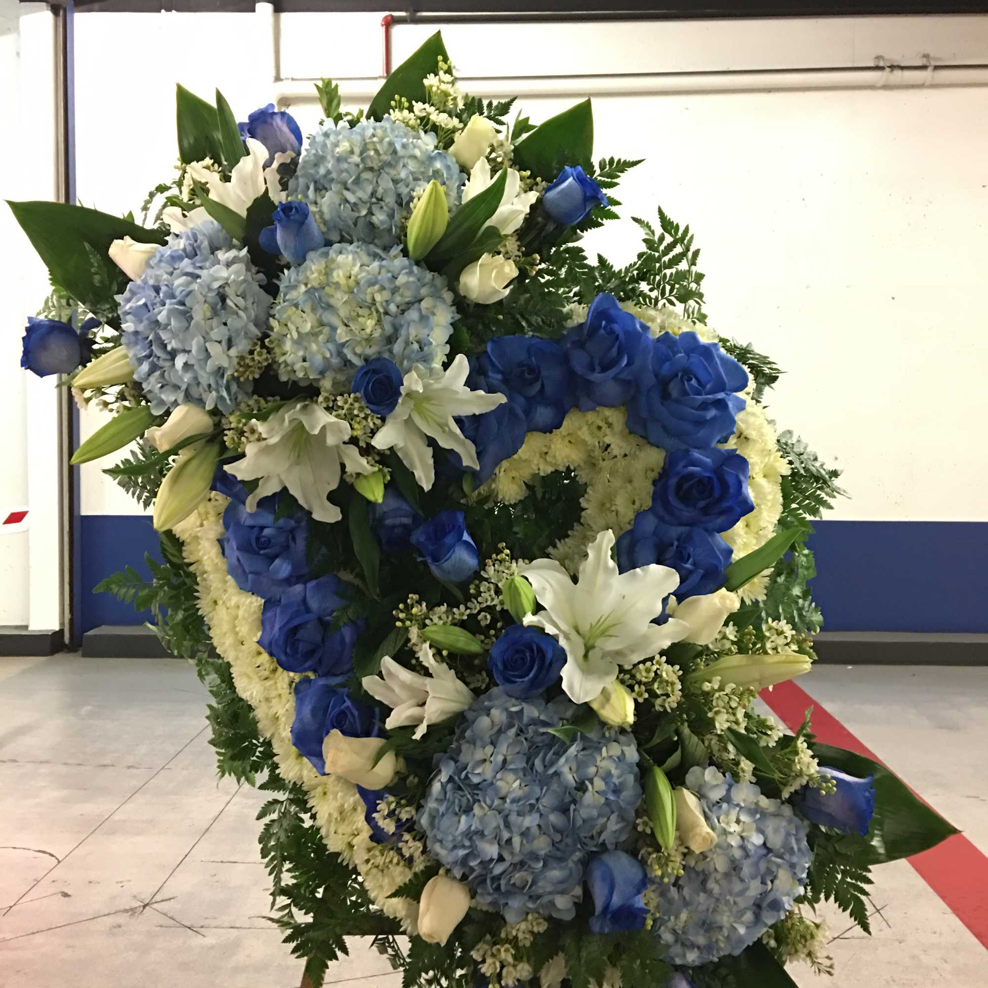 Large blue and white funeral wreath on an easel