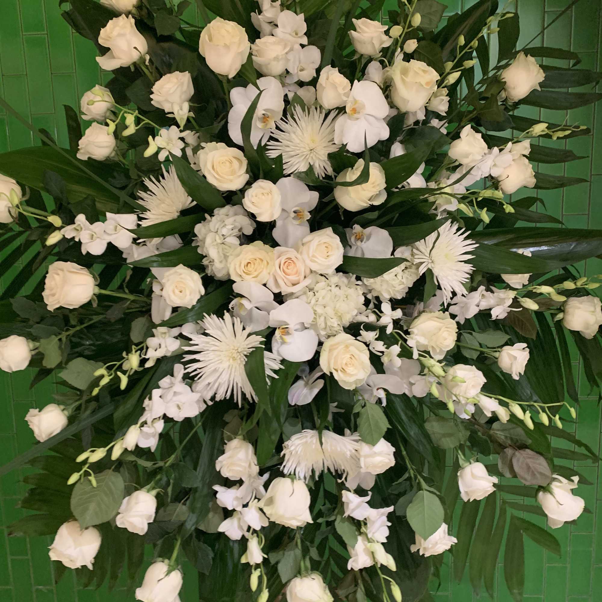 Large white floral spray with roses and orchids against green tiles