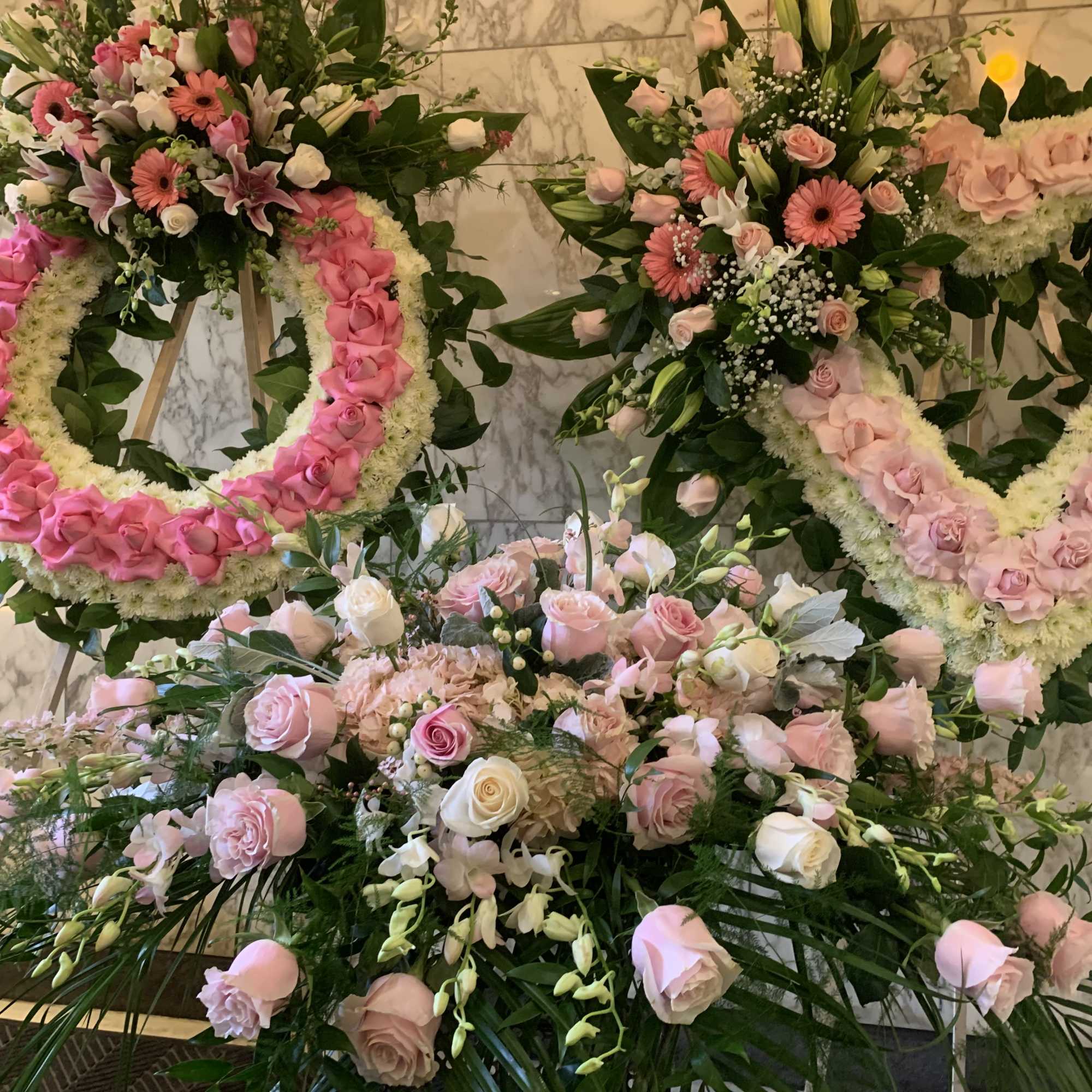 Pink and white floral wreaths and bouquets arranged on stands