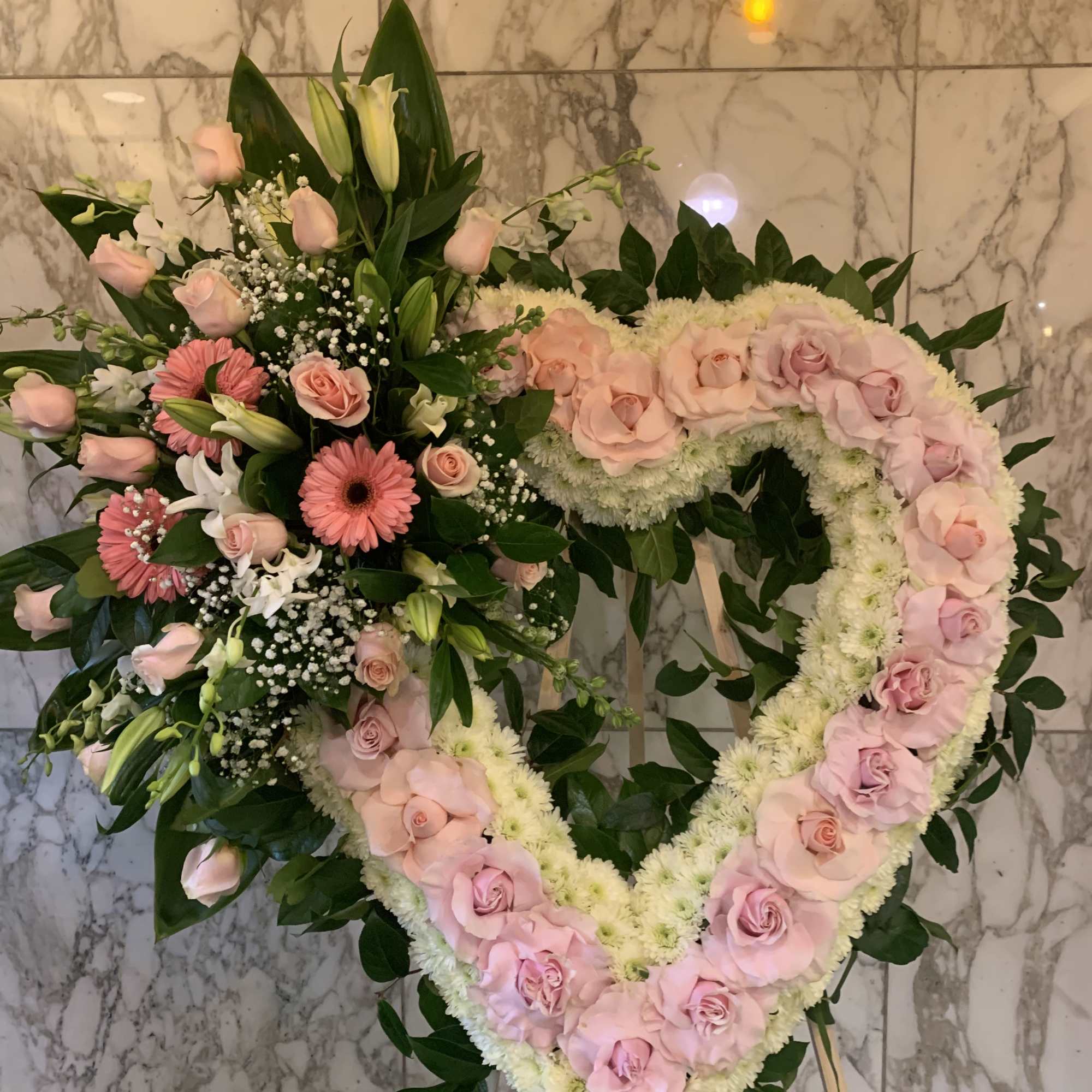 Two pink floral funeral wreaths with roses and lilies on stands