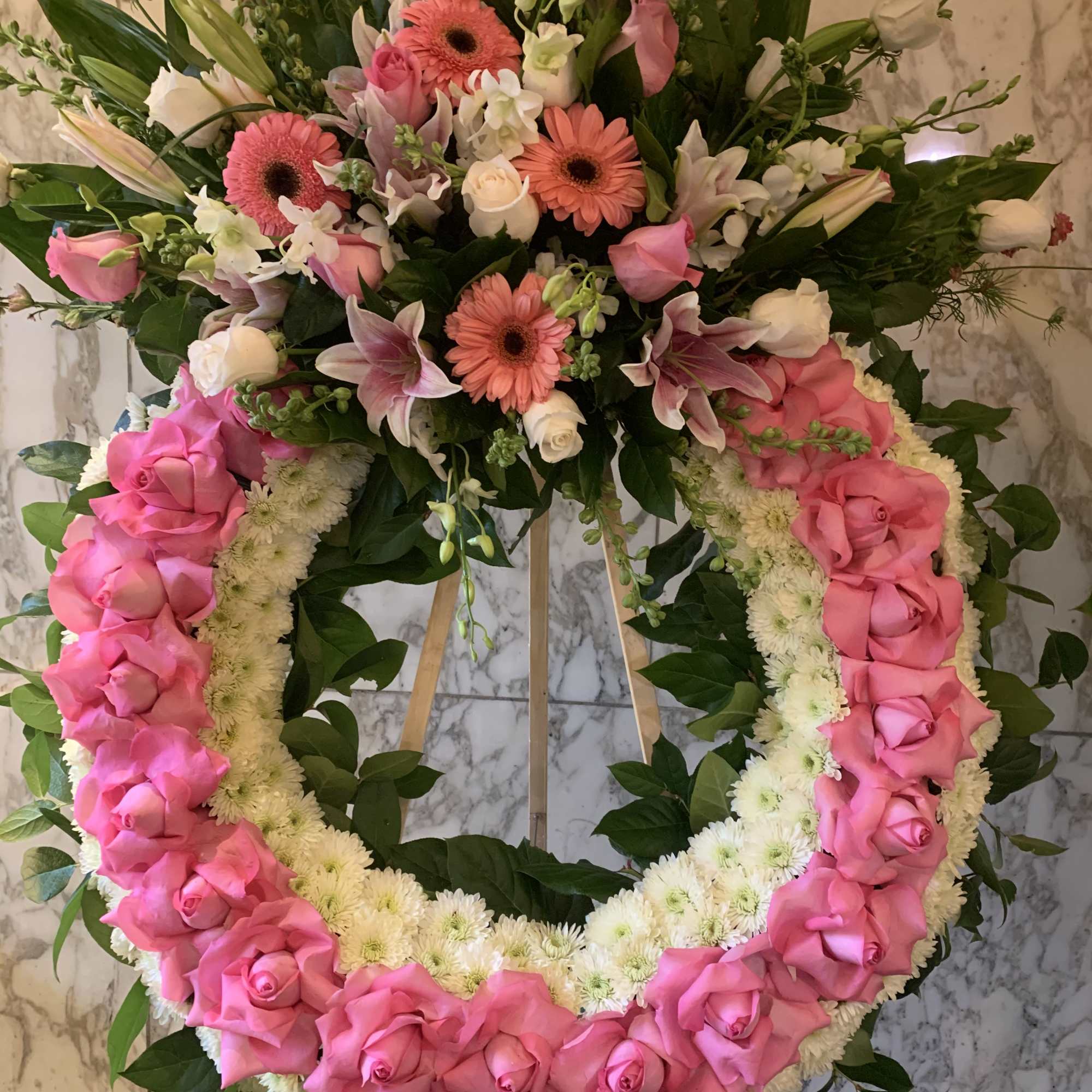 Pink and white floral funeral wreath on an easel