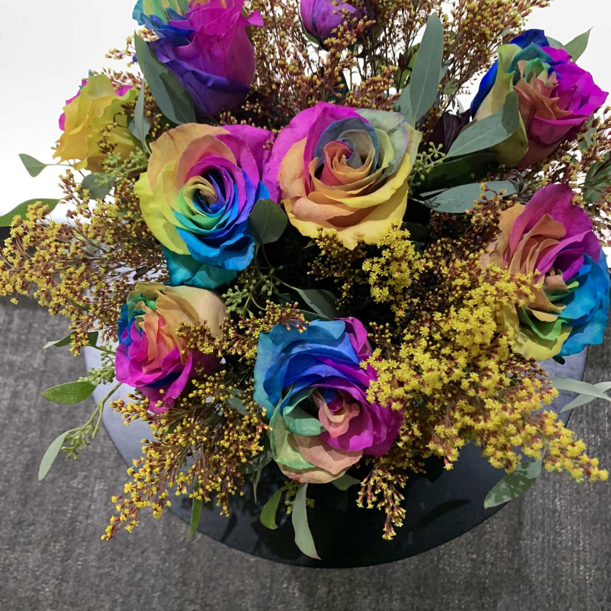 Bouquet of rainbow-colored roses with yellow filler flowers