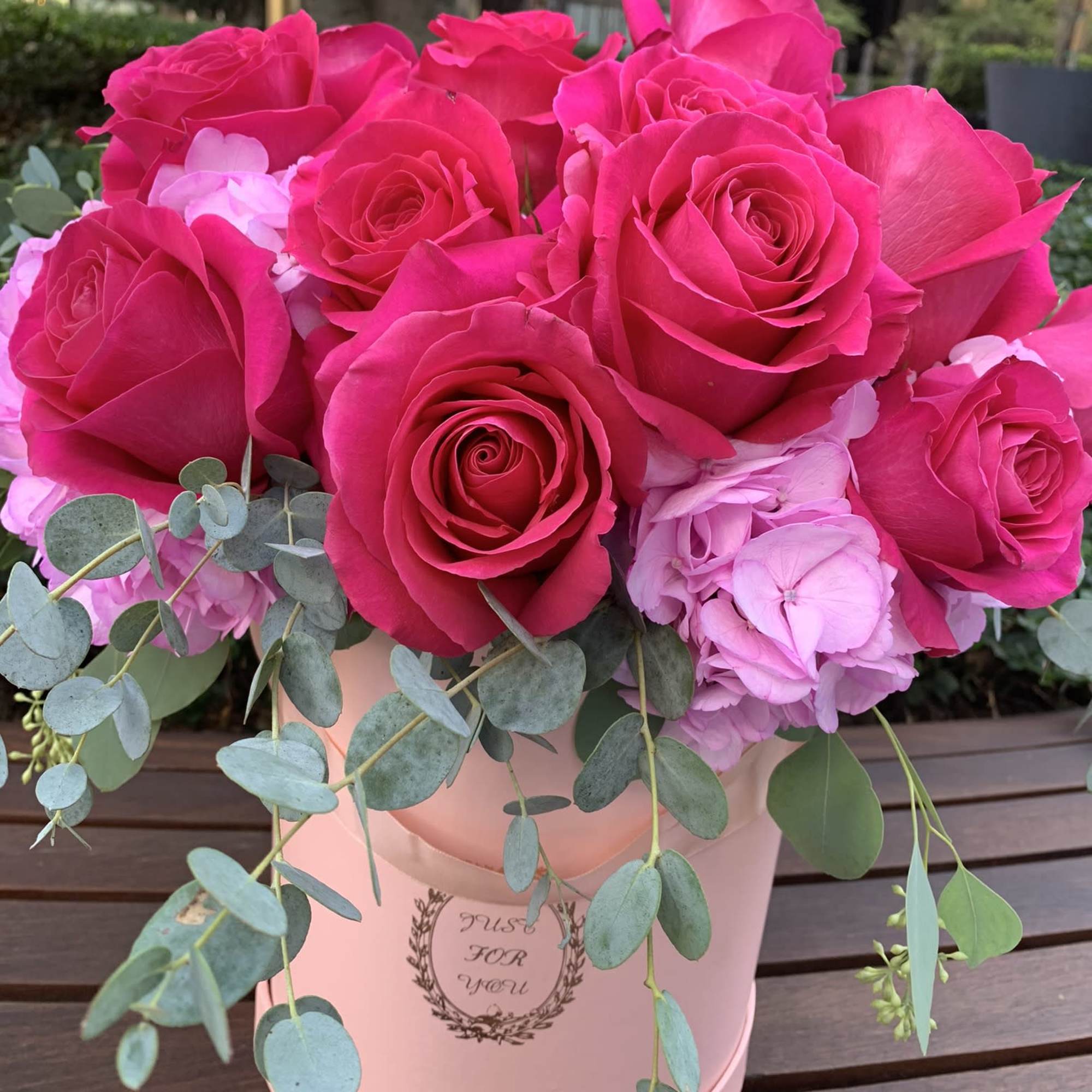 Pink roses and hydrangeas in a blush hatbox with trailing eucalyptus