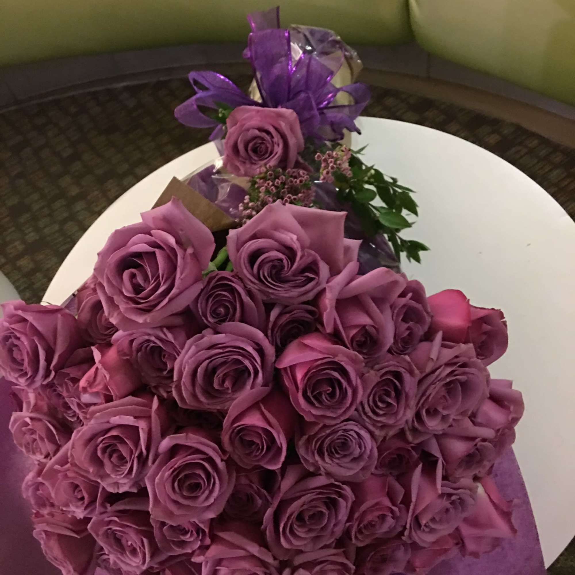 Large bouquet of purple roses wrapped in purple paper with ribbon