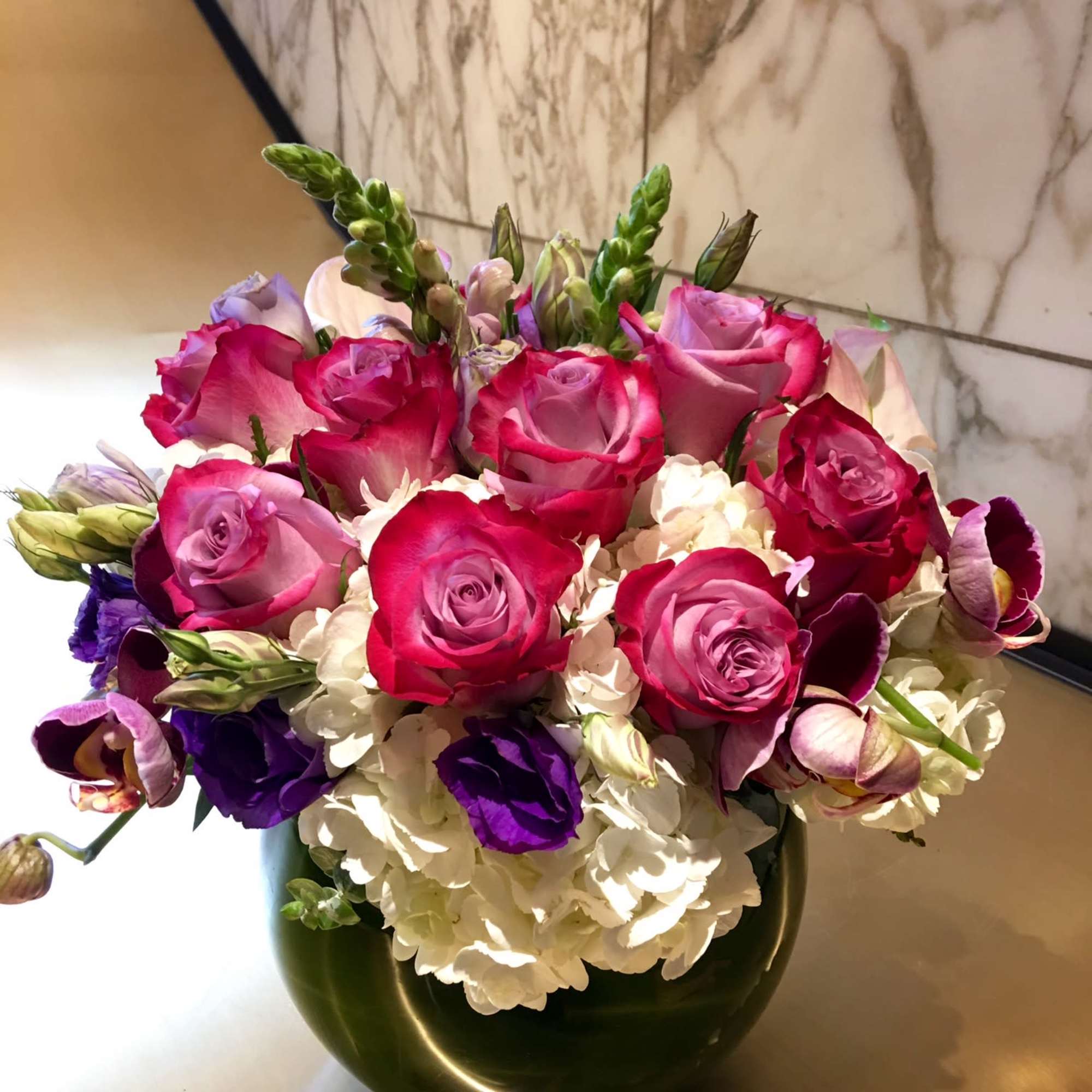 Pink and purple roses arranged in a dark green vase