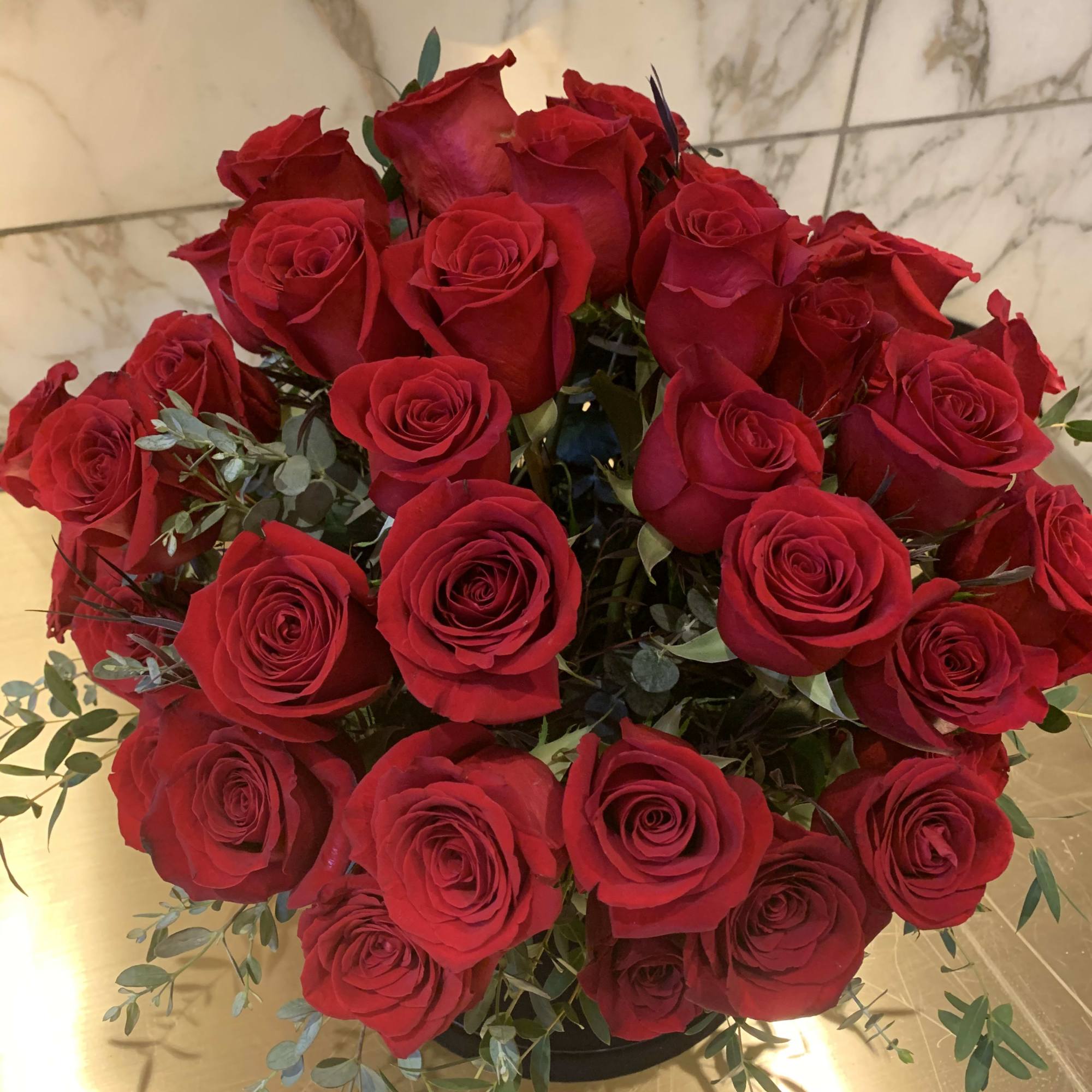 Bouquet of red roses with eucalyptus in a low container