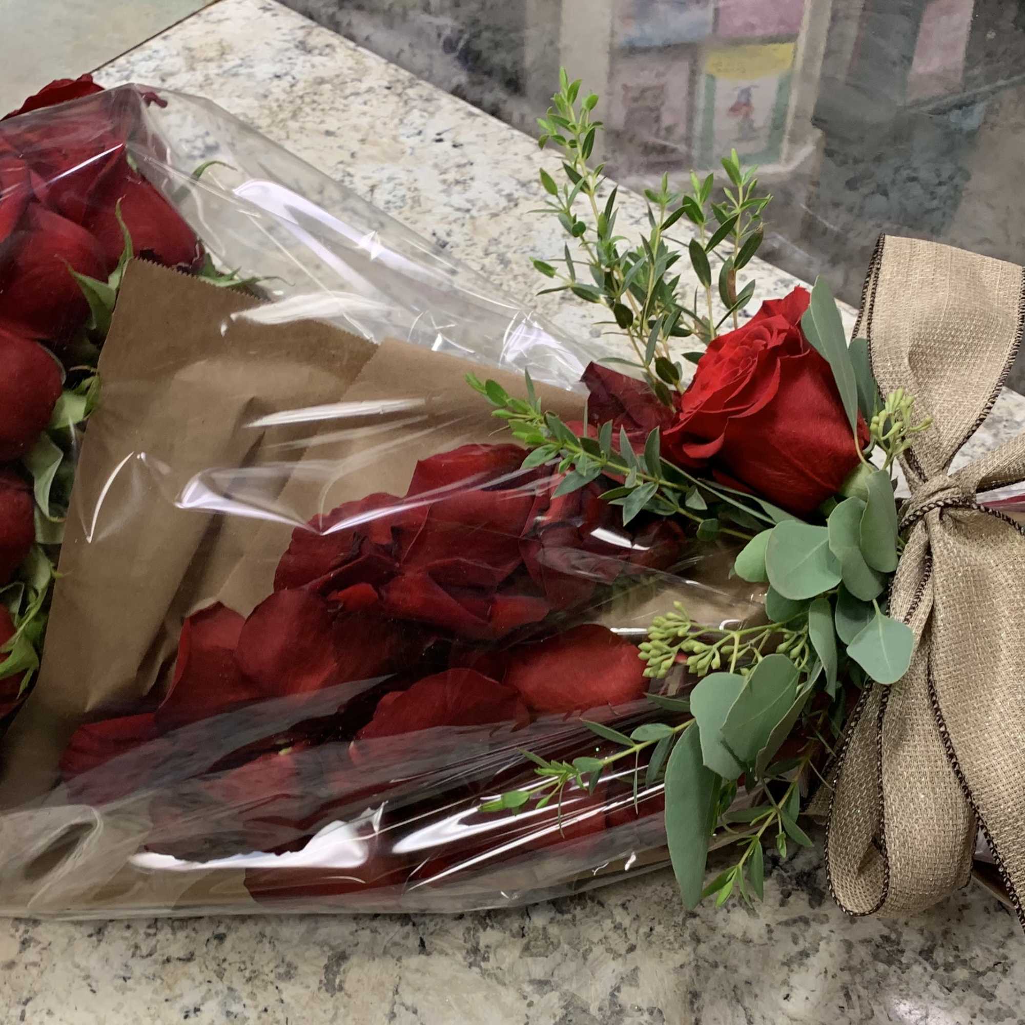Two bouquets of red roses wrapped in brown paper and clear plastic