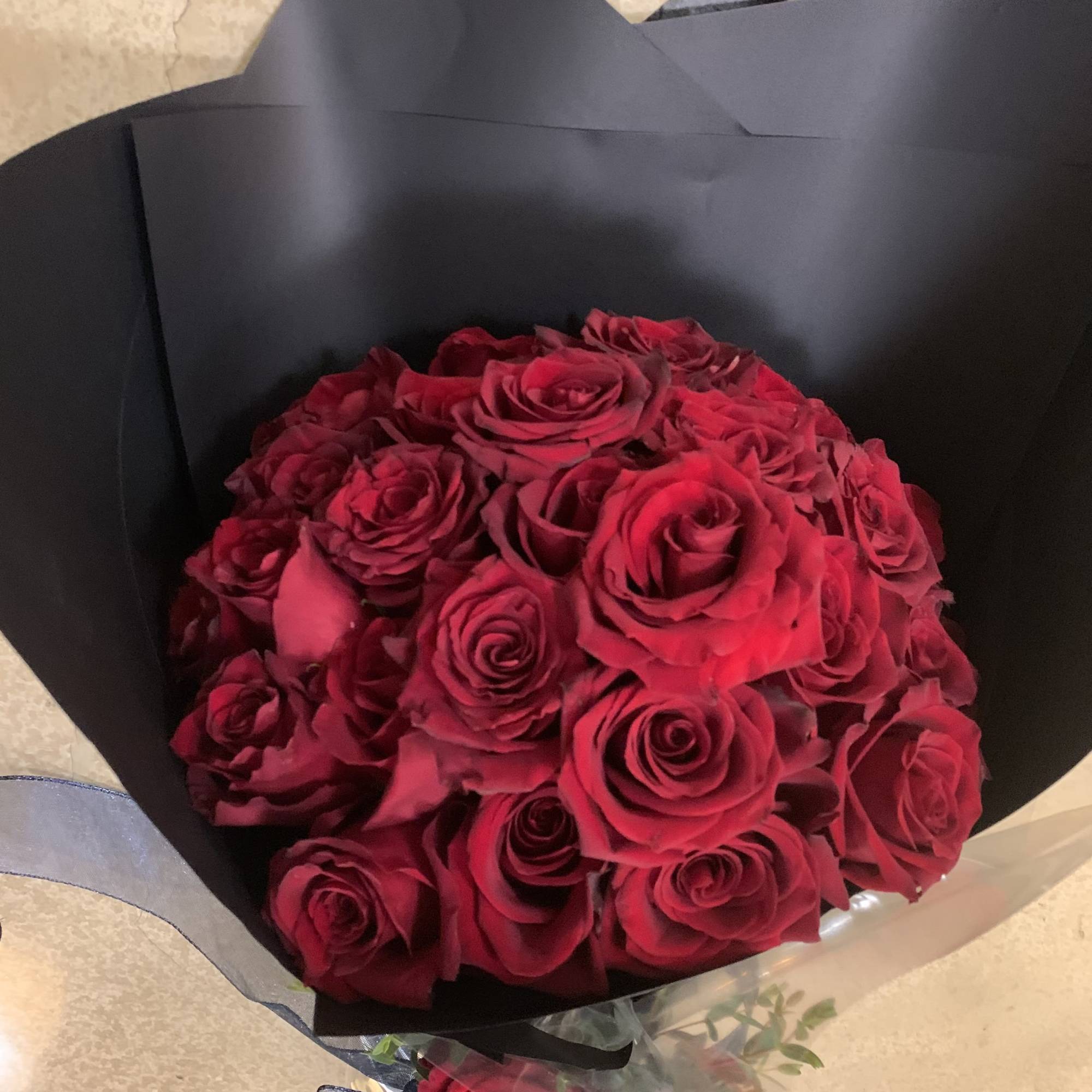 Bouquet of red roses wrapped in black paper with a ribbon